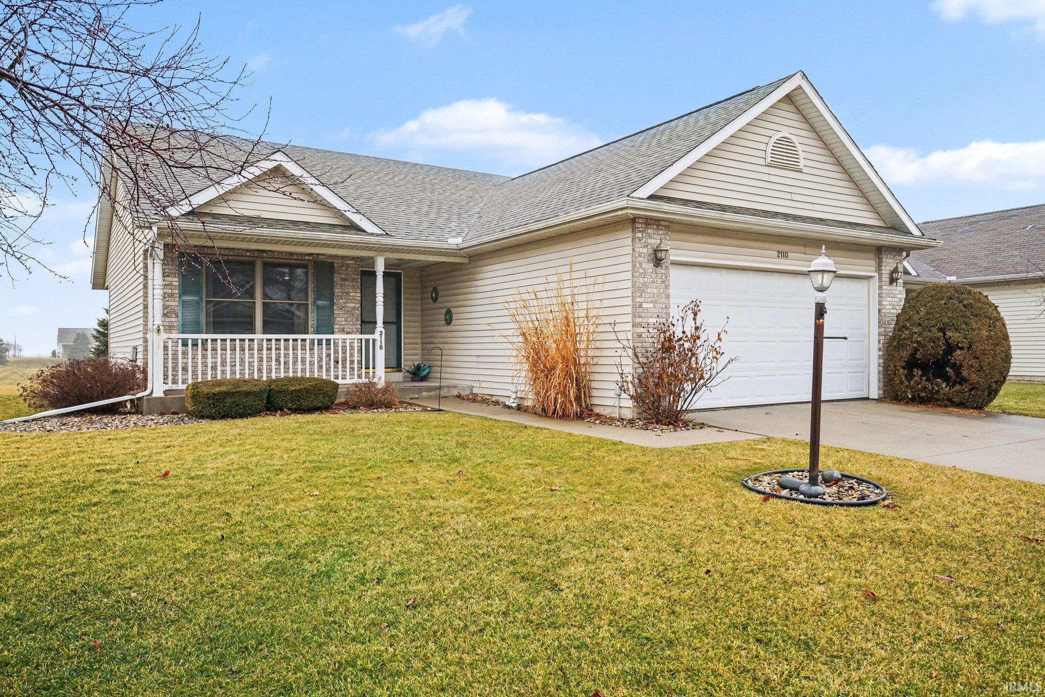 Ranch-style house featuring a porch, a front yard, concrete driveway, and brick siding