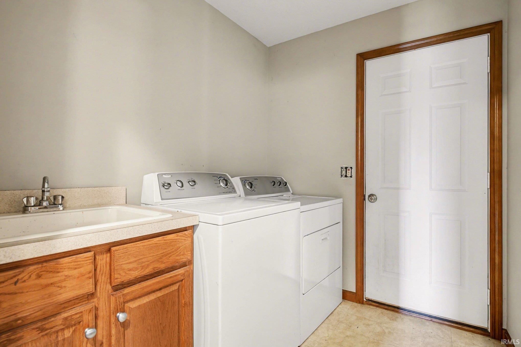Laundry room with separate washer and dryer, cabinet space, and light flooring