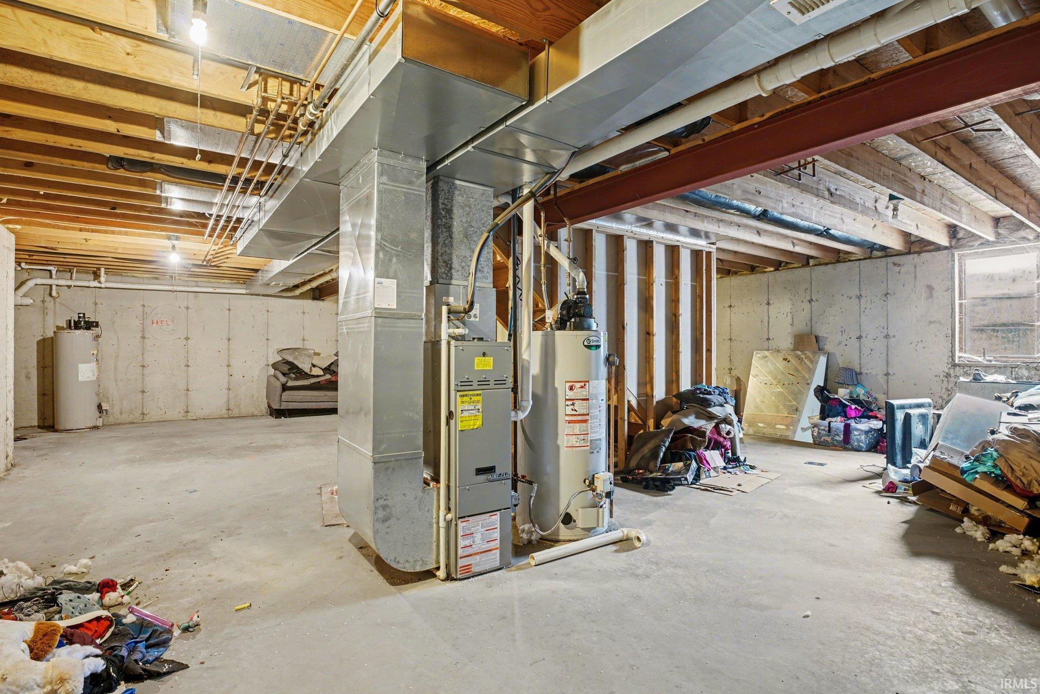 Unfinished basement with heating unit, gas water heater, and water heater