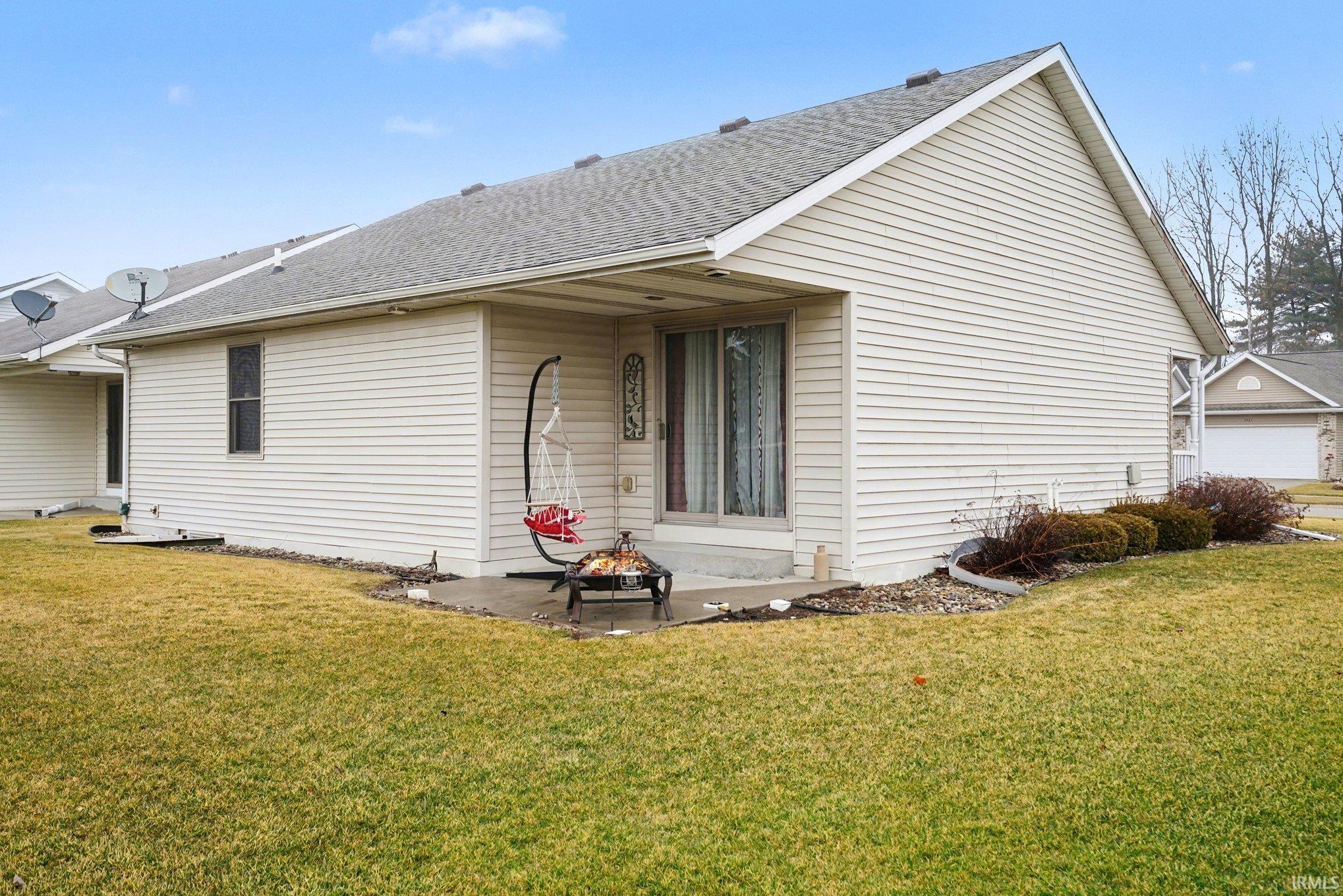 View of side of home featuring a lawn, roof with shingles, and a patio area