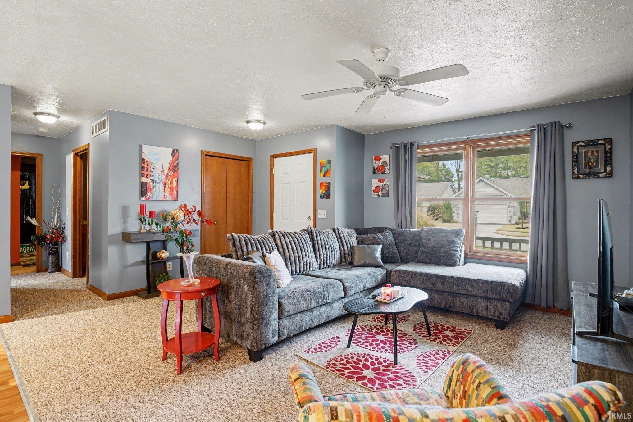 Living room with a textured ceiling and a ceiling fan