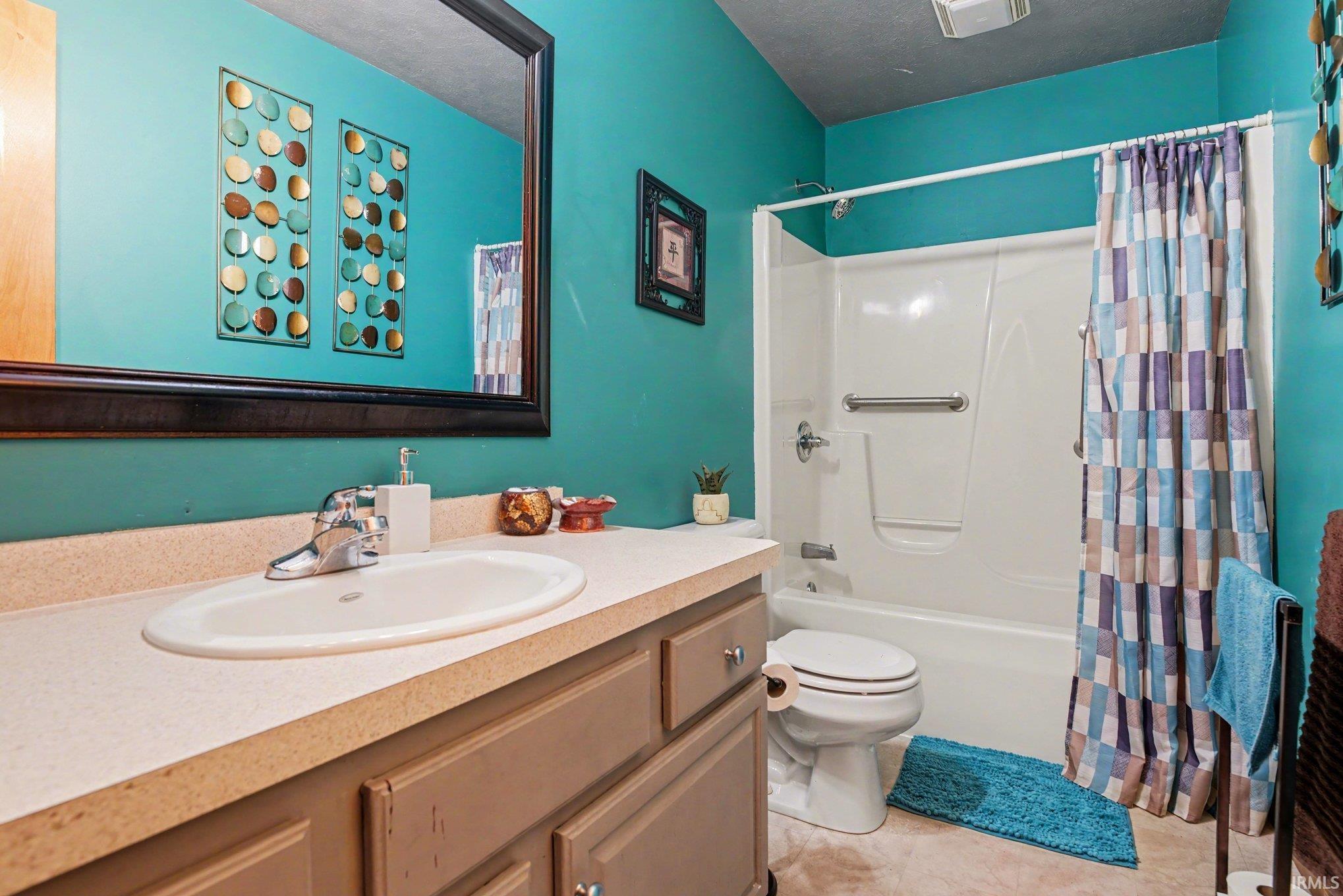 Full bath featuring vanity, a textured ceiling, and shower / tub combo