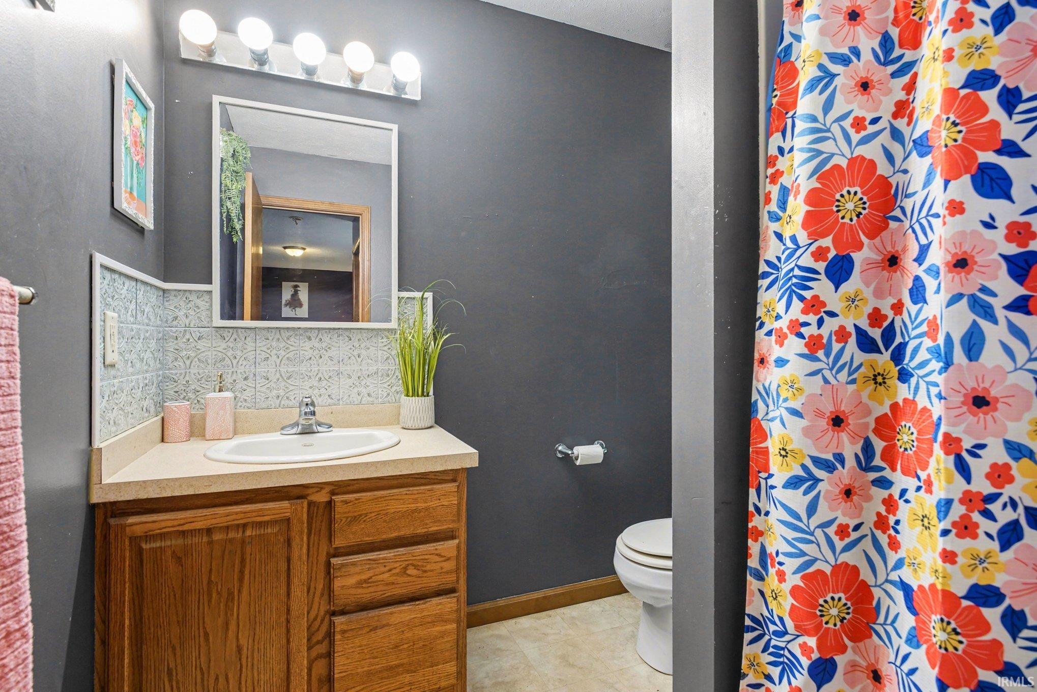 Bathroom featuring vanity, tasteful backsplash, a shower with curtain, and light tile patterned floors