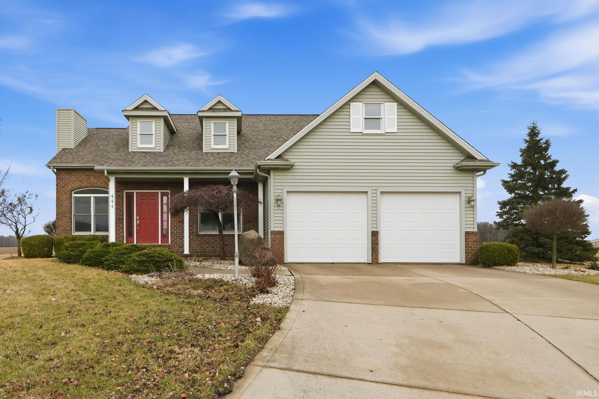 View of front of property featuring brick siding, concrete driveway, covered porch, a shingled roof, and a garage