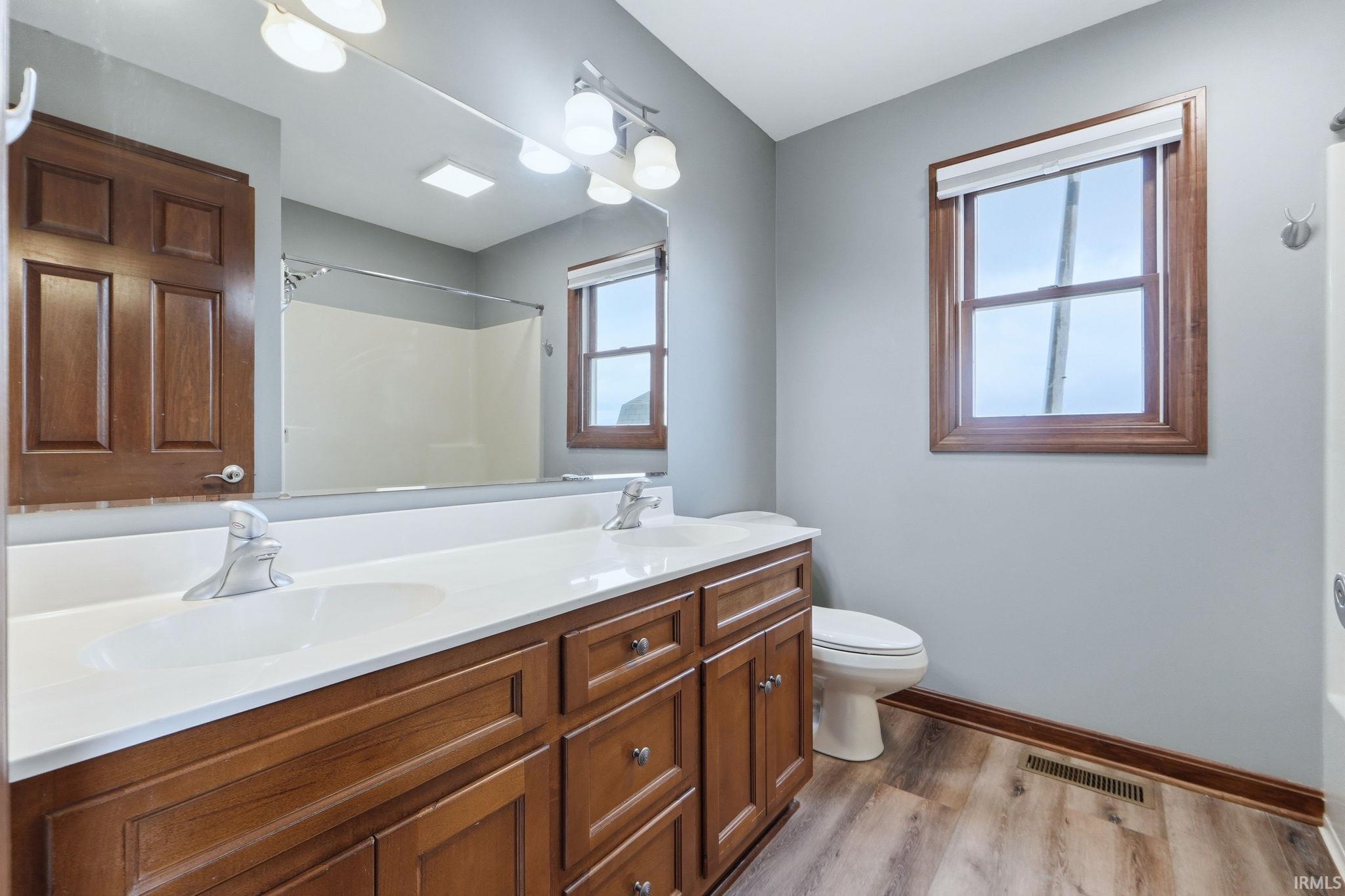 Bathroom featuring double vanity, a shower, light wood-type flooring, and a bath