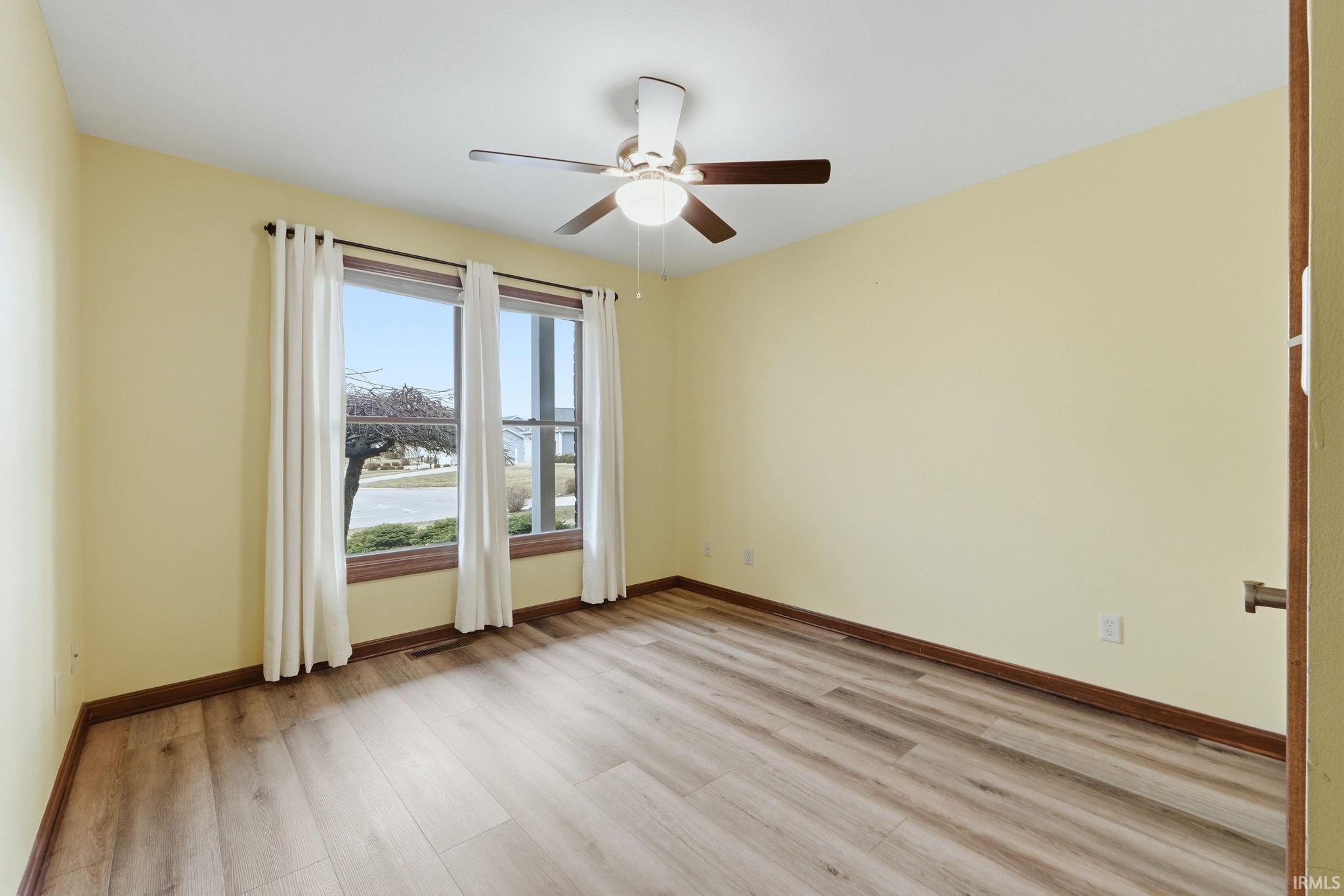 Empty room with light wood-style flooring, ceiling fan, and a water view