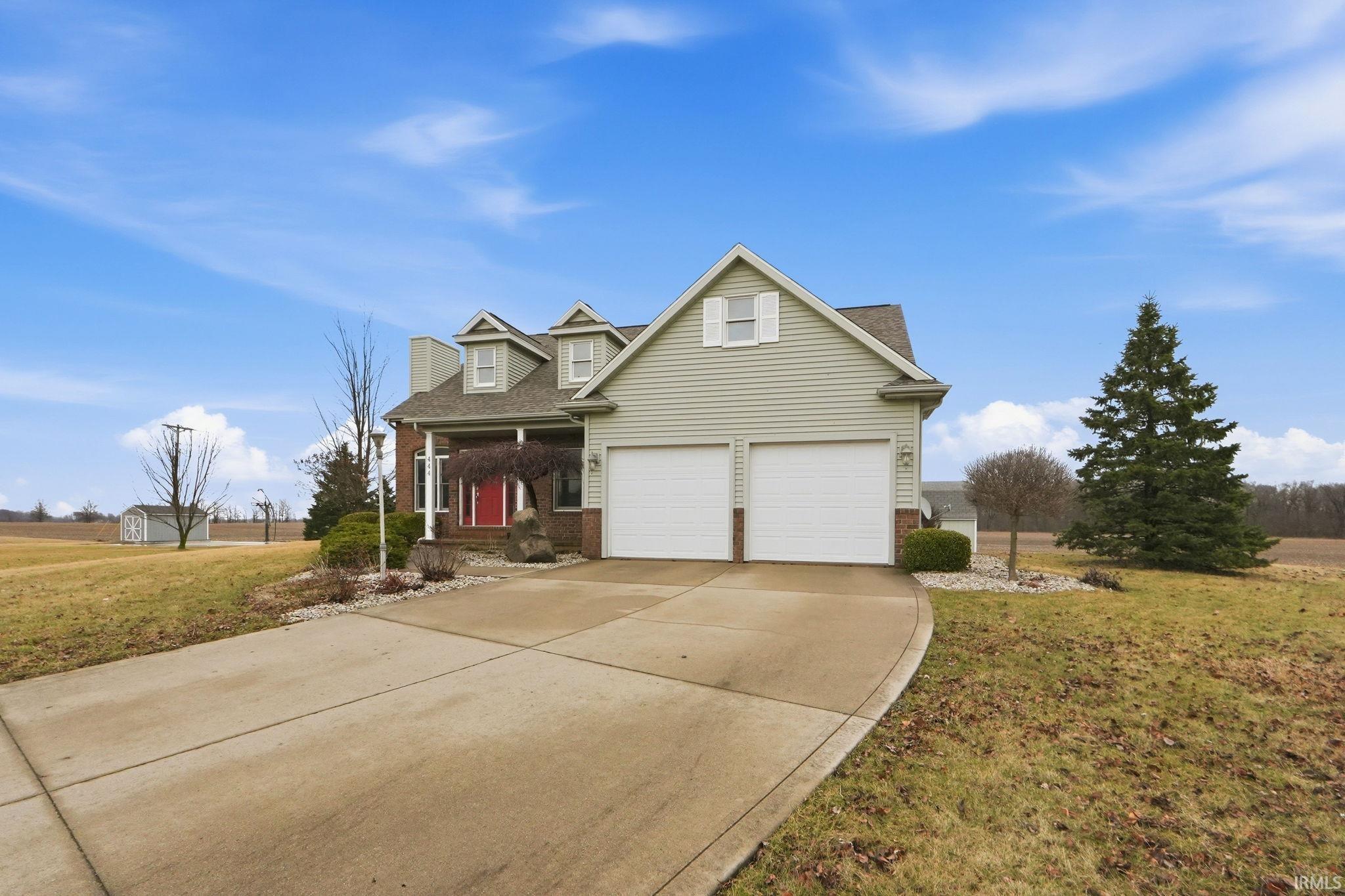 Traditional-style home featuring brick siding, a front lawn, a porch, driveway, and roof with shingles