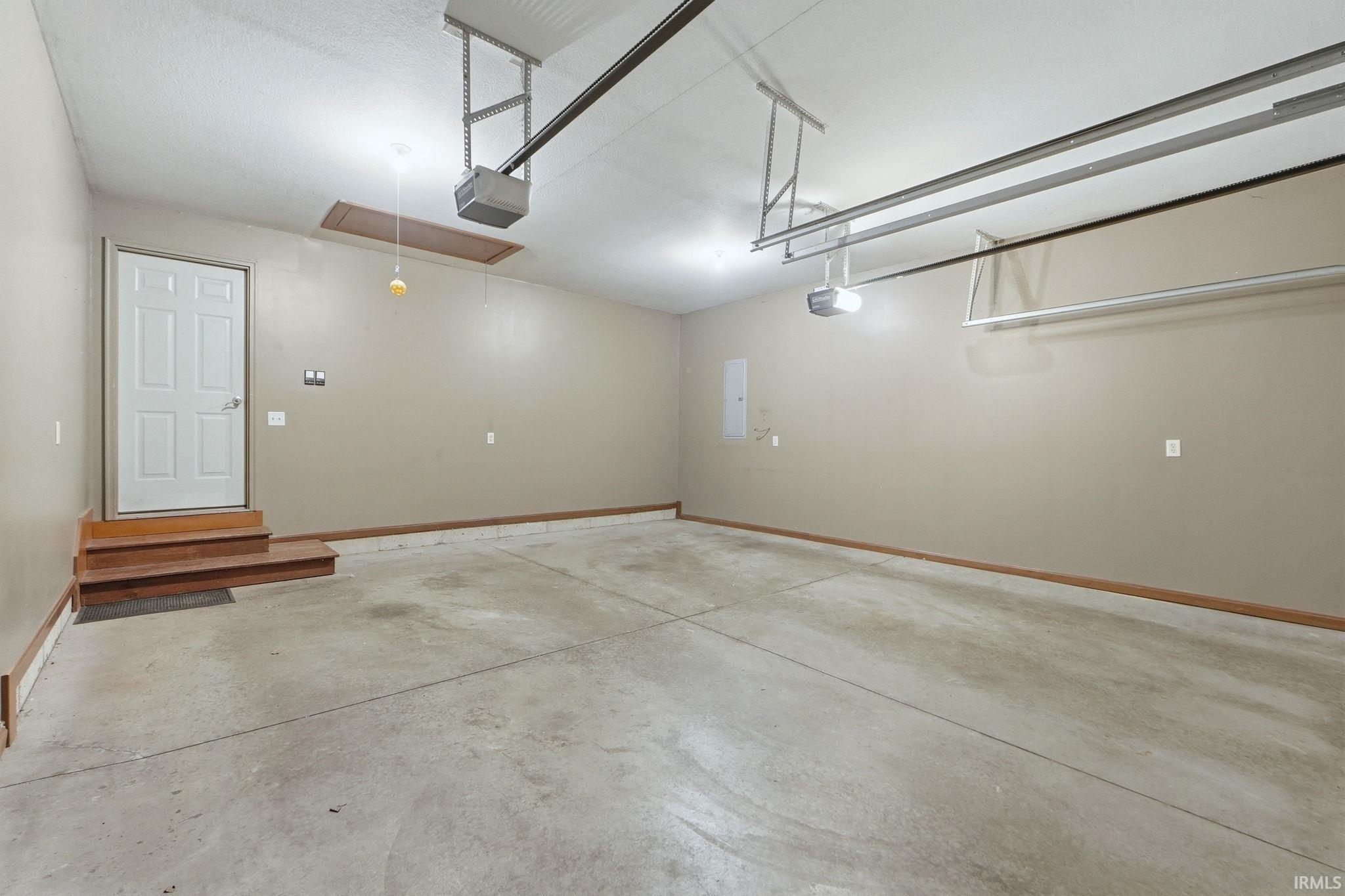Garage featuring a garage door opener and baseboards