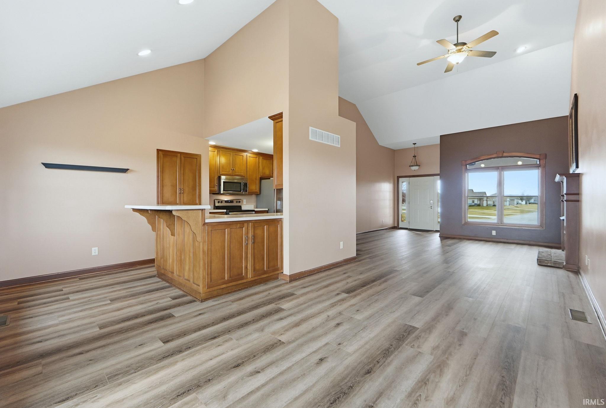 Kitchen with open floor plan, light countertops, wood finish cabinetry, ceiling fan, and recessed lighting