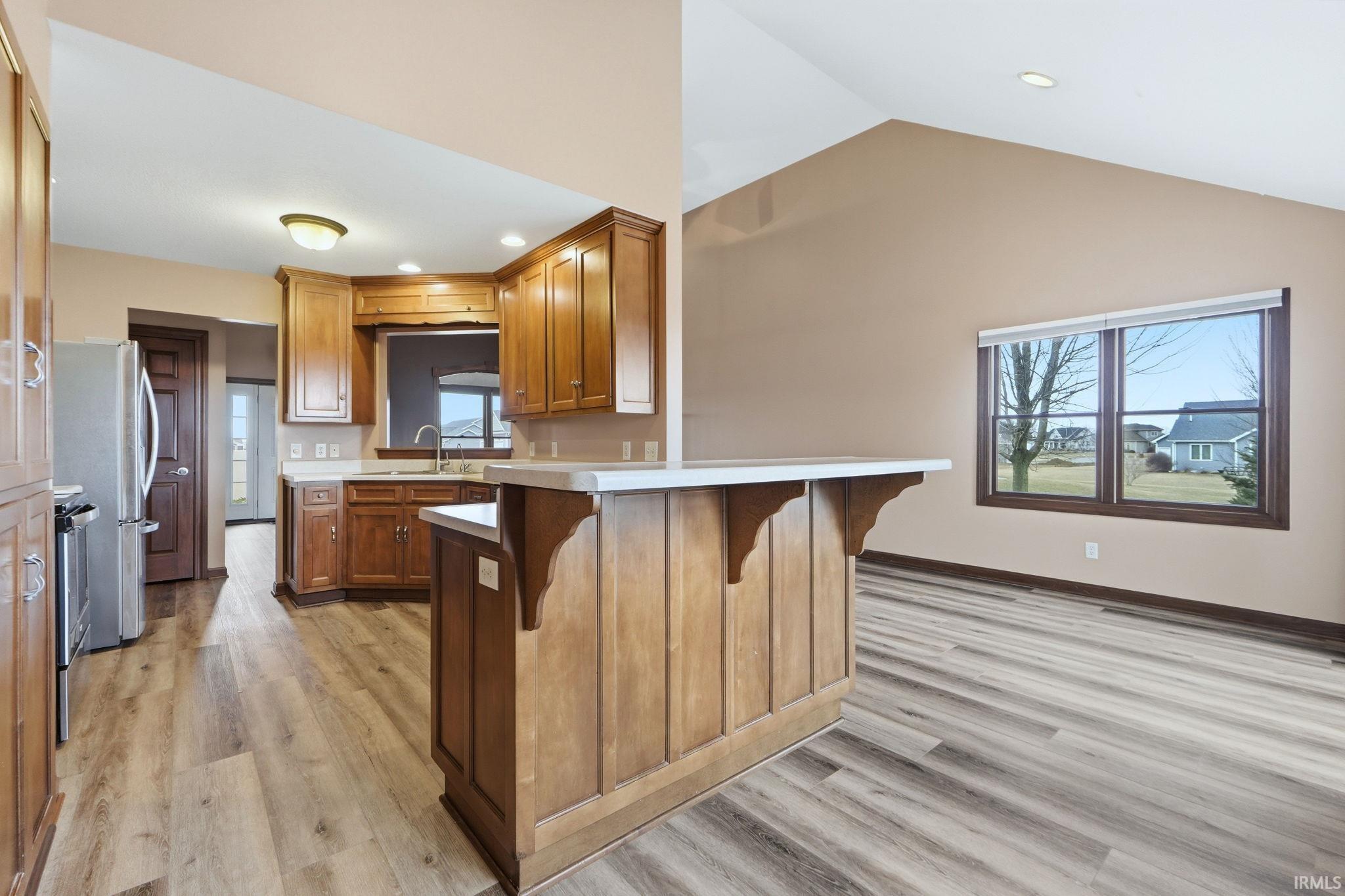 Kitchen featuring wood finish cabinetry, light countertops, a breakfast bar area, recessed lighting, and light wood-style floors