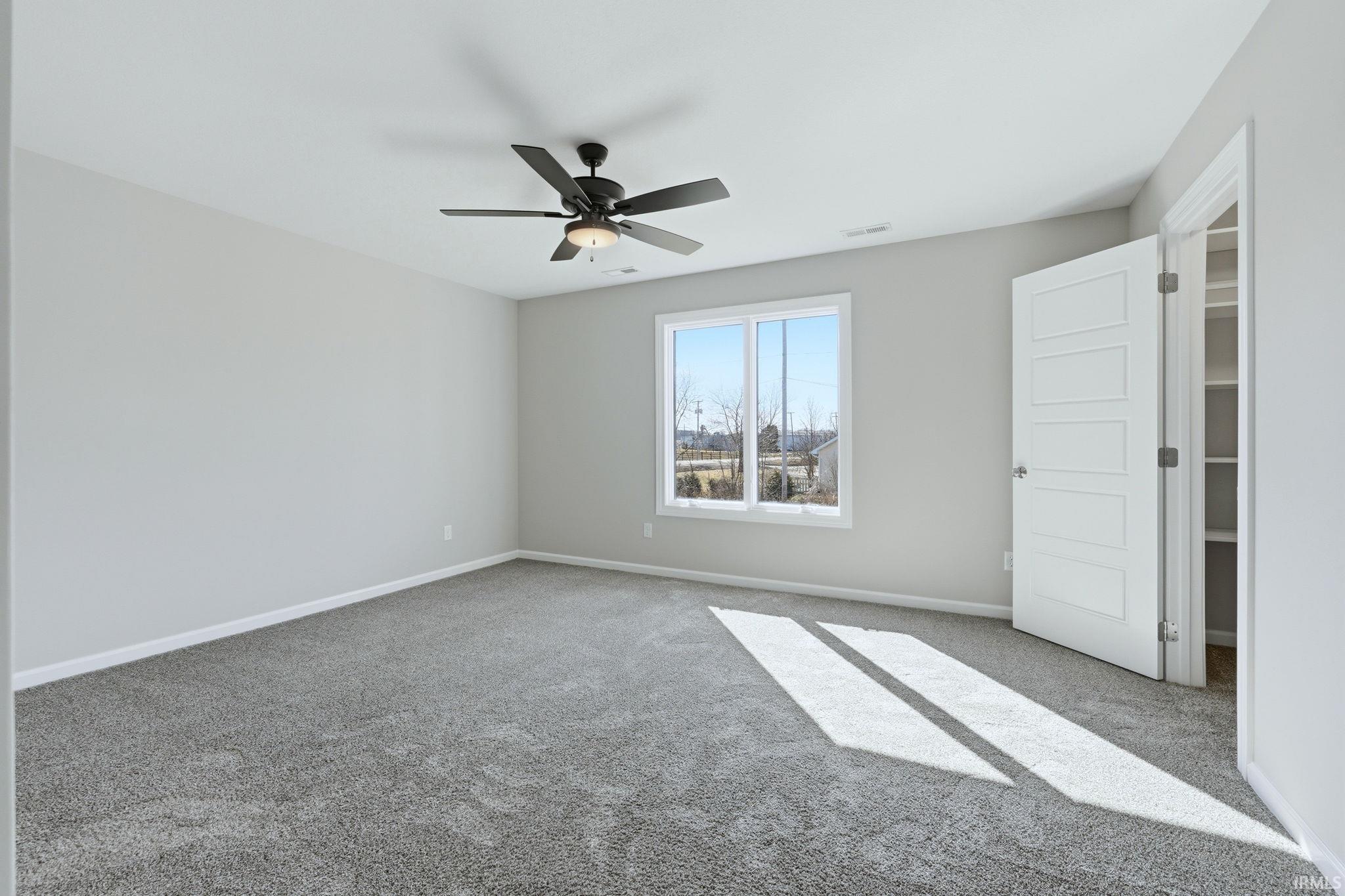Unfurnished bedroom featuring carpet flooring, a ceiling fan, and a spacious closet