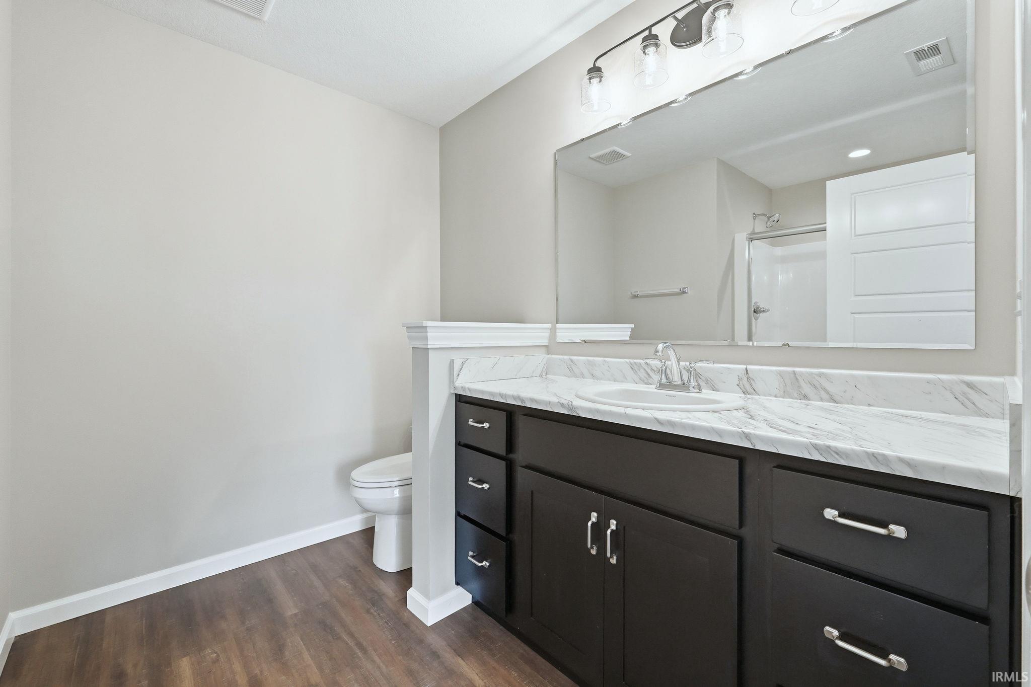 Full bathroom with vanity, a stall shower, and dark wood-style floors