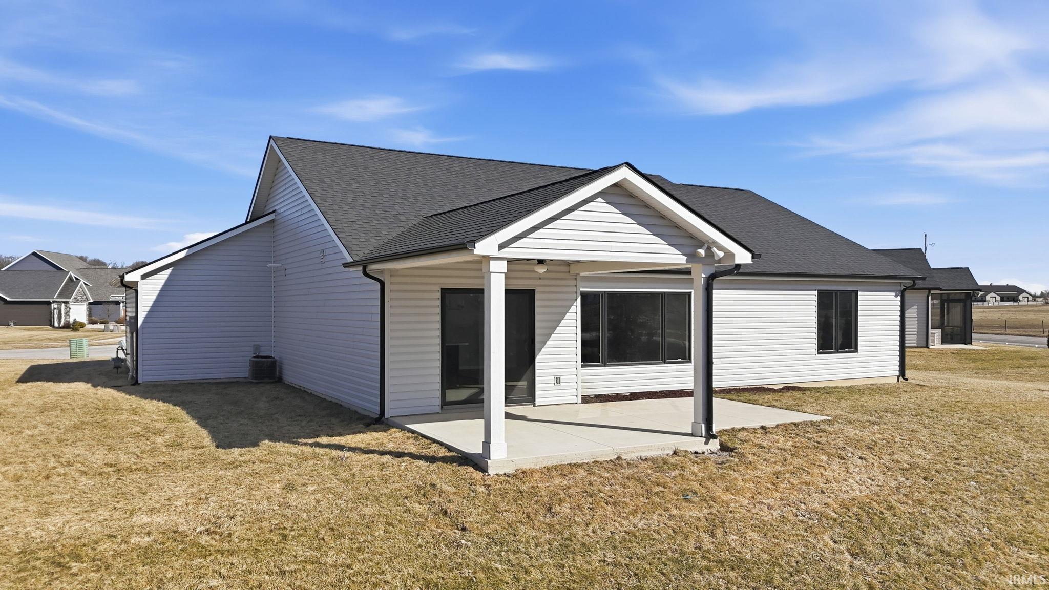 Back of property with a lawn, roof with shingles, and a patio