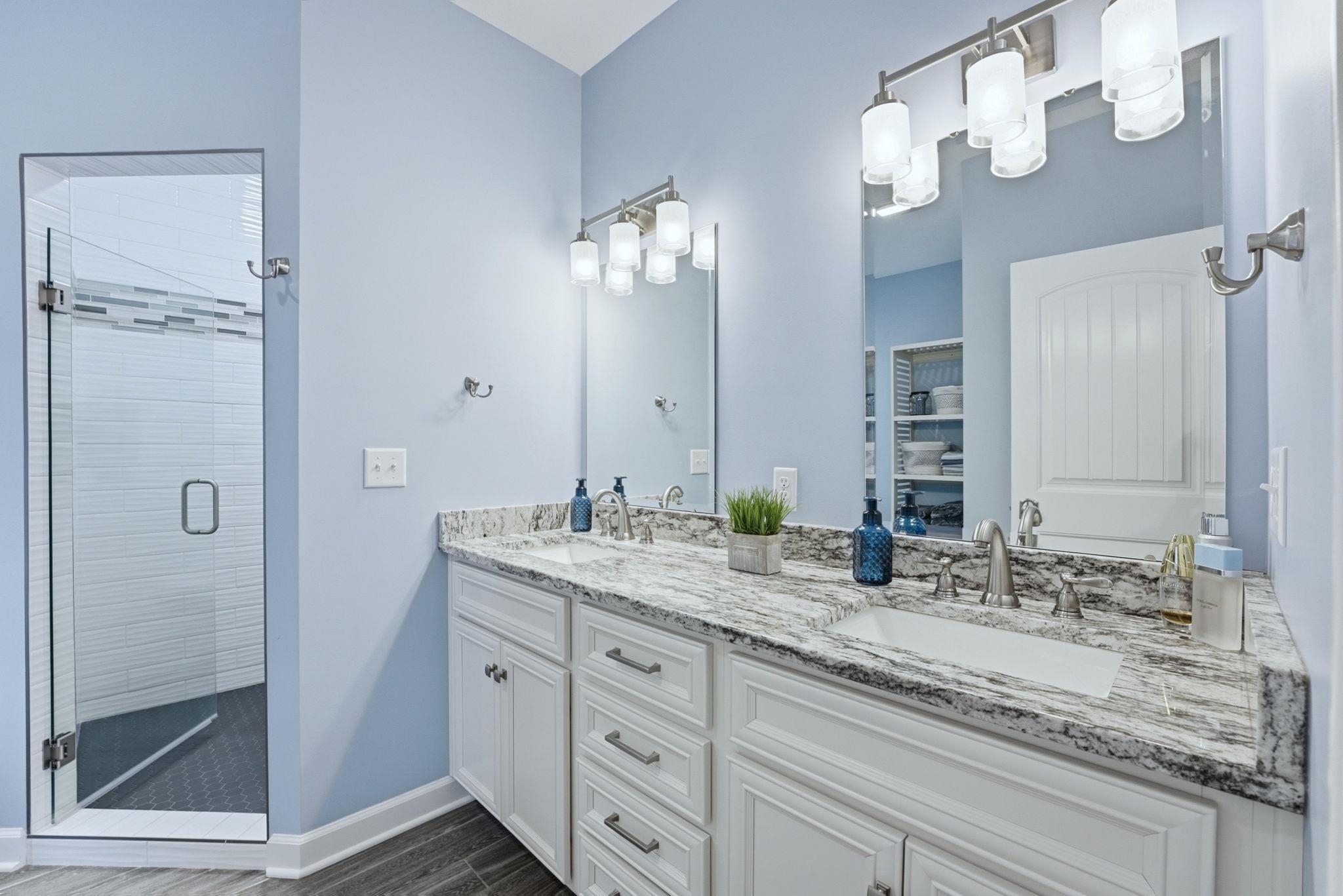 Bathroom featuring double vanity, a stall shower, and dark wood-style floors