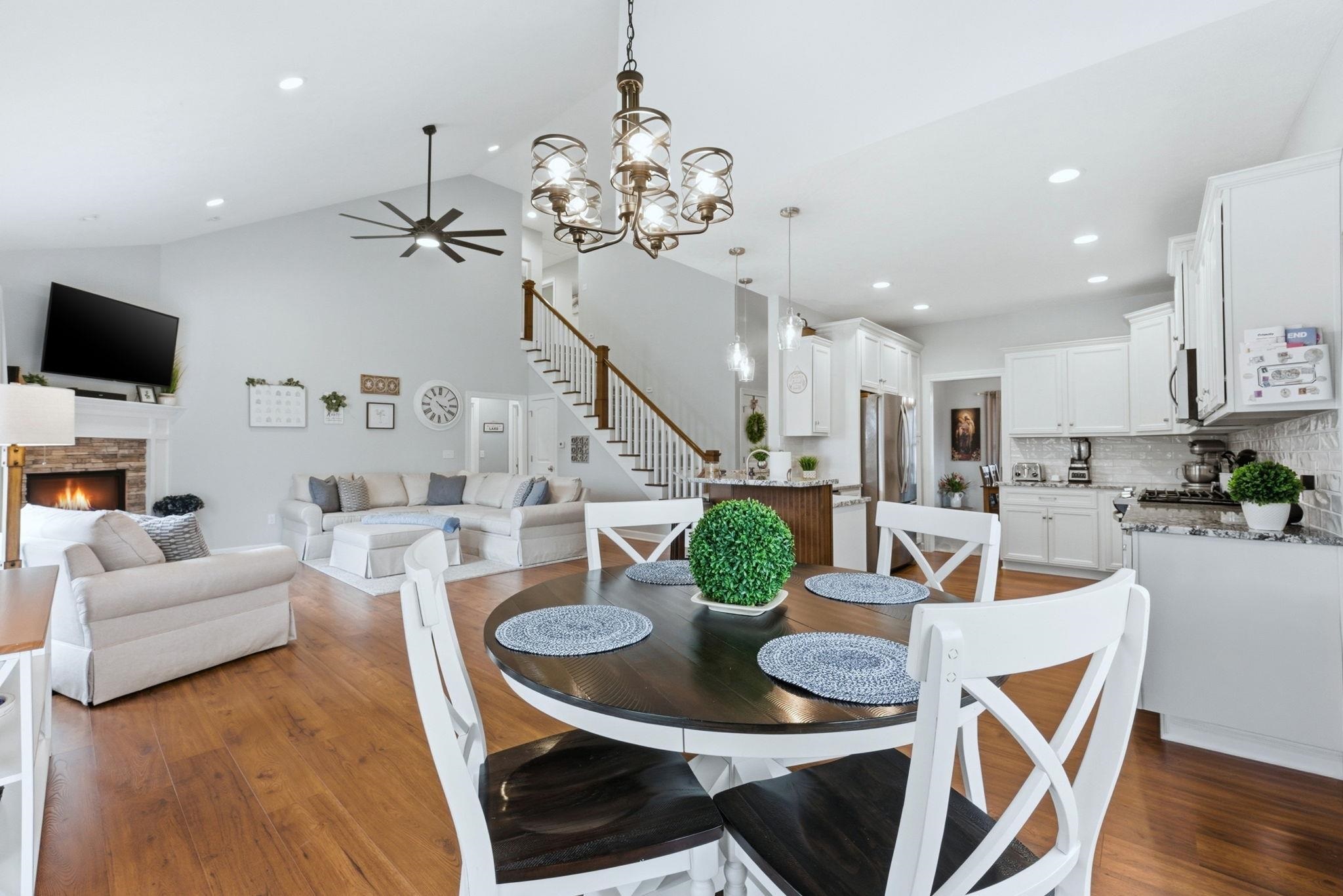 Dining space featuring a fireplace, hanging lights, dark wood-style flooring, ceiling fan, and vaulted ceiling