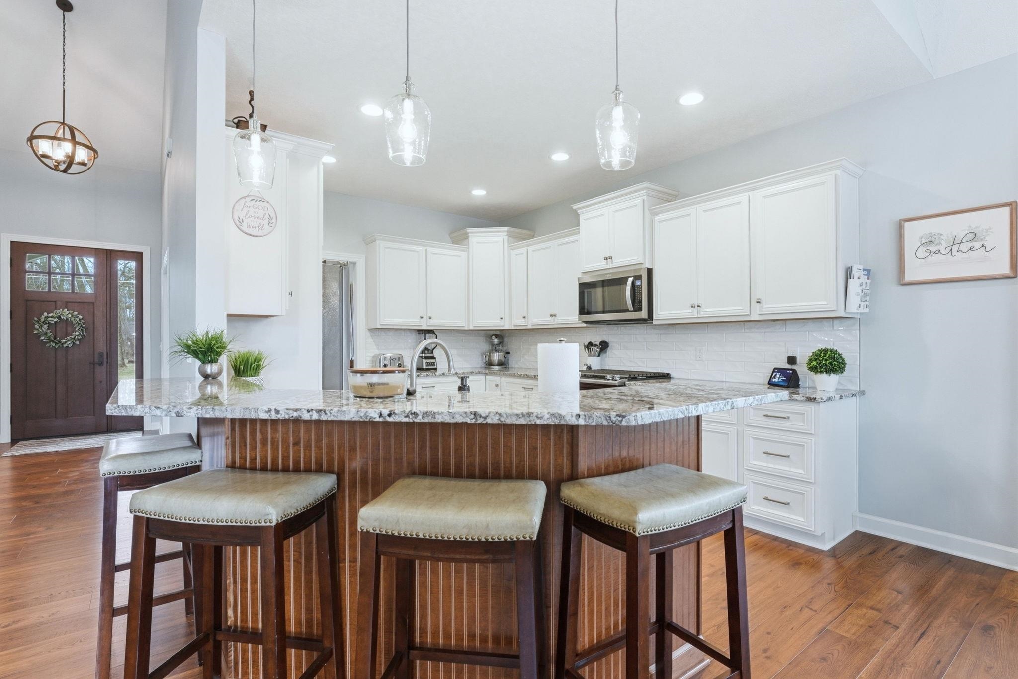 Kitchen with white cabinets, light stone counters, and a kitchen breakfast bar