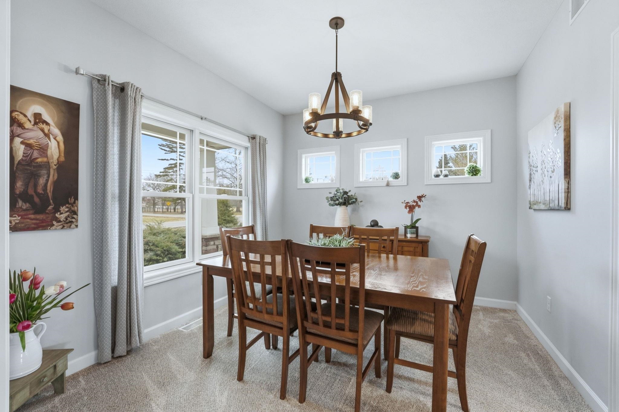Dining space with light colored carpet and a chandelier