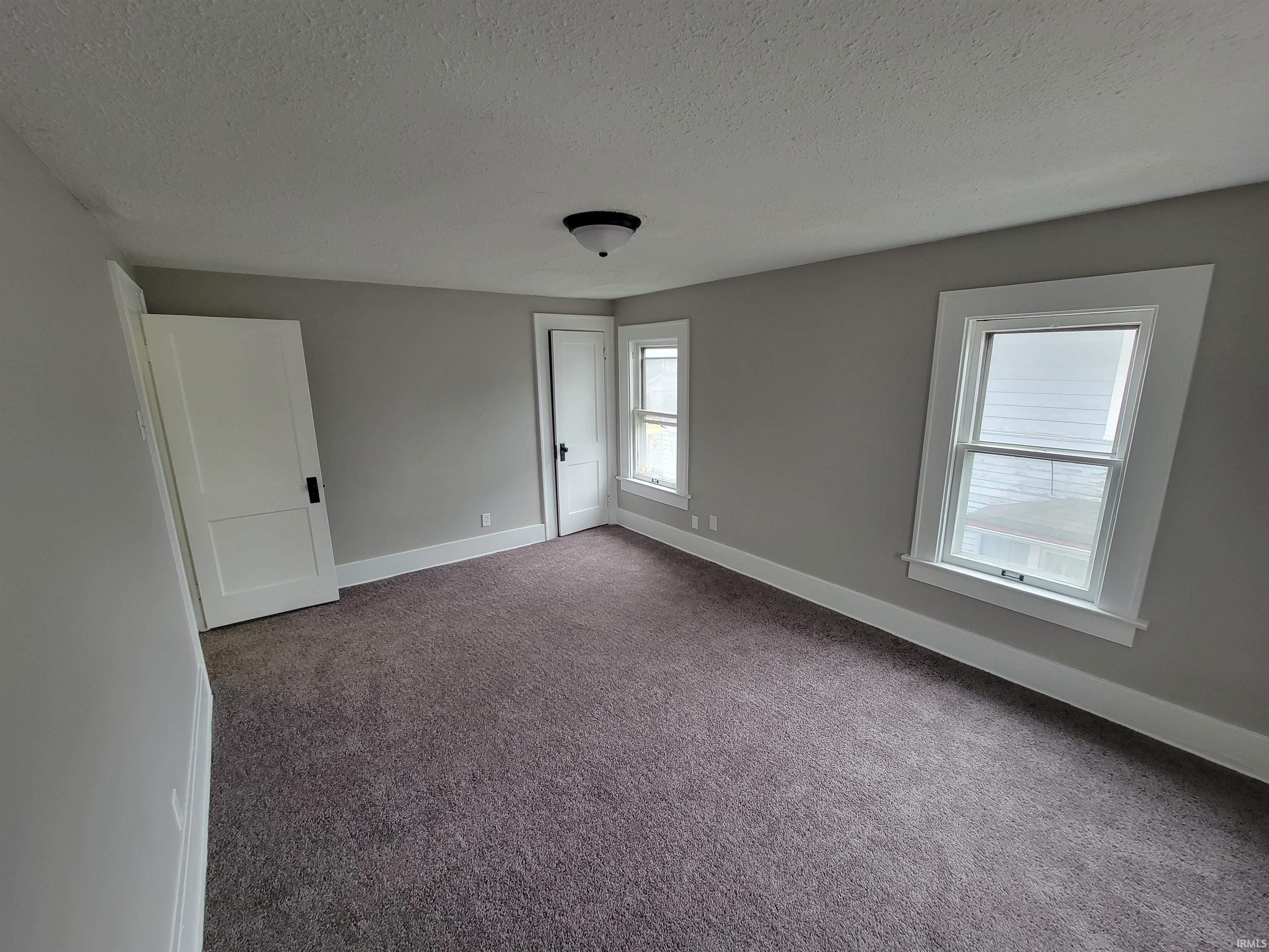 Unfurnished bedroom with dark colored carpet and a textured ceiling