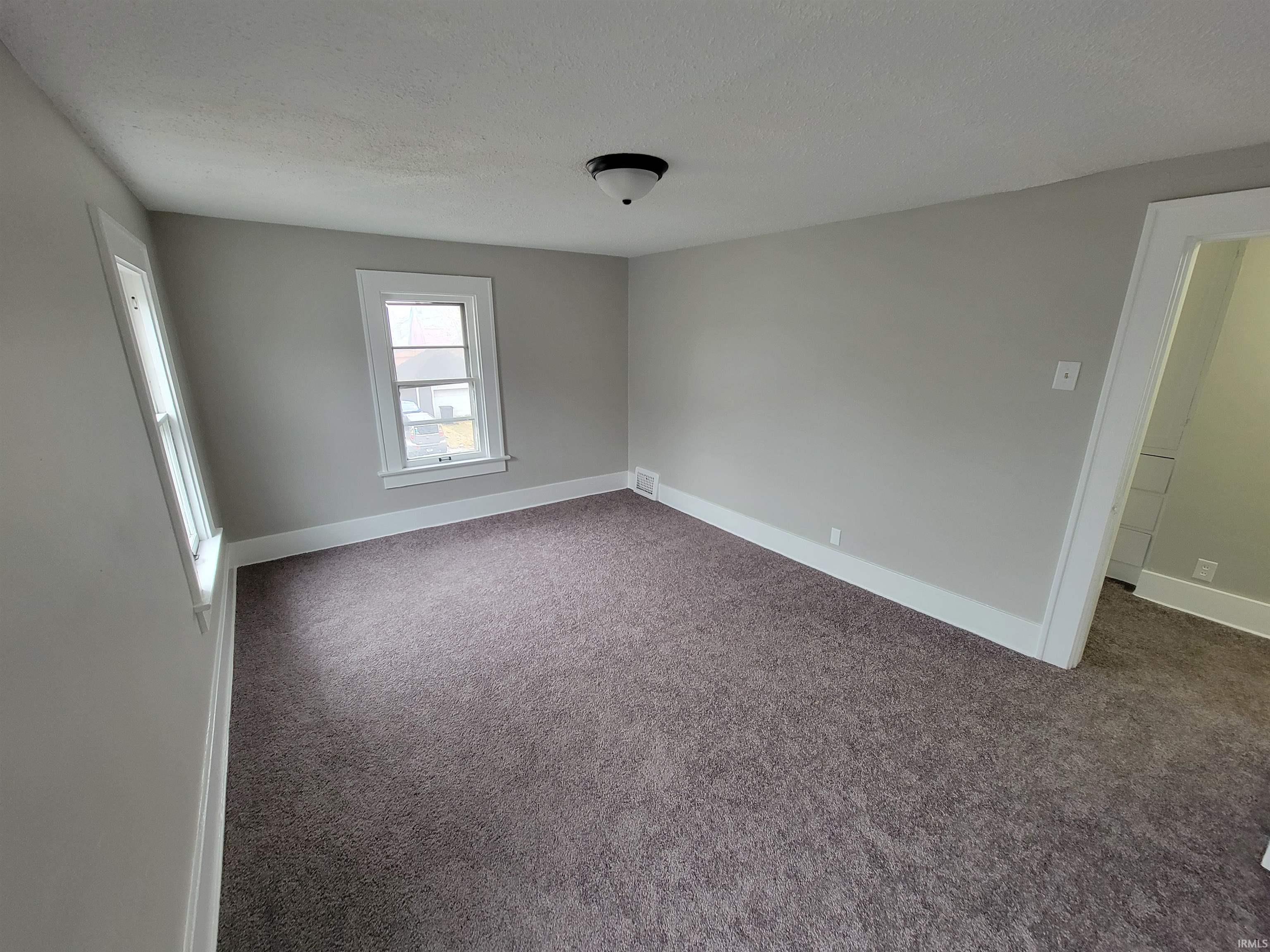 Carpeted spare room with baseboards and a textured ceiling