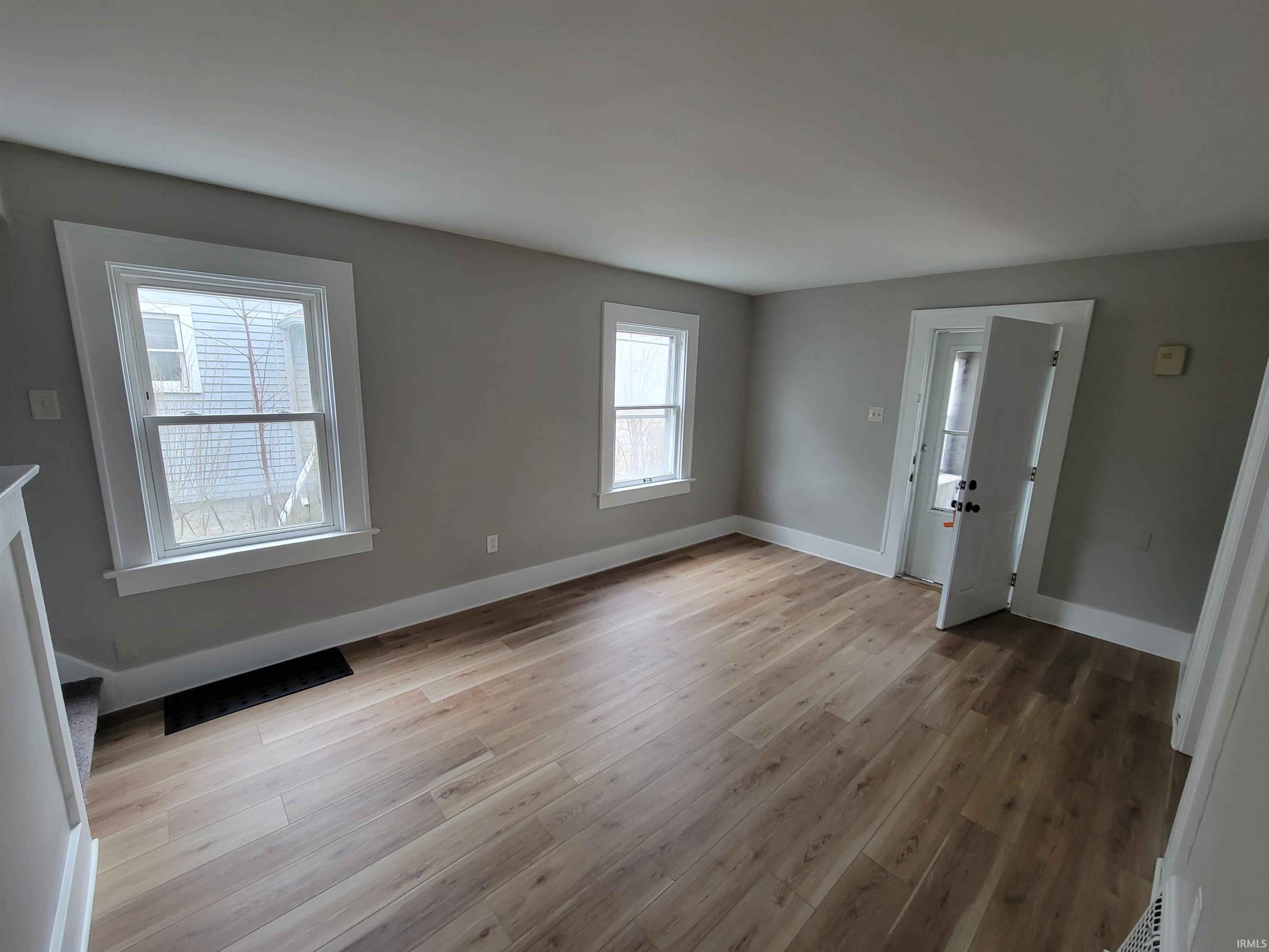 Unfurnished living room featuring baseboards and light wood finished floors