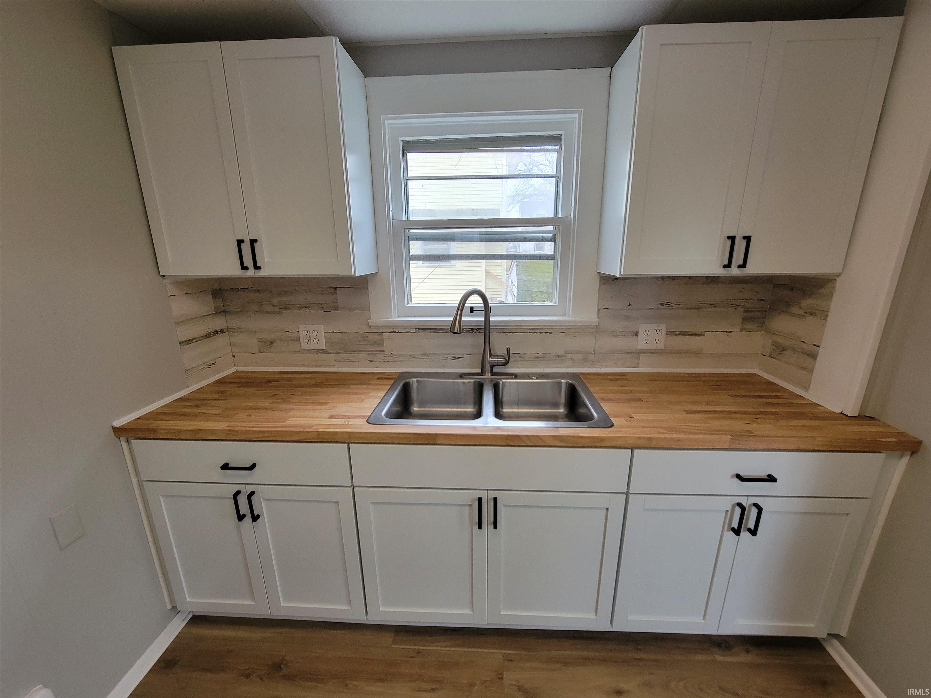 Kitchen with wooden counters, white cabinetry, and dark wood-style flooring