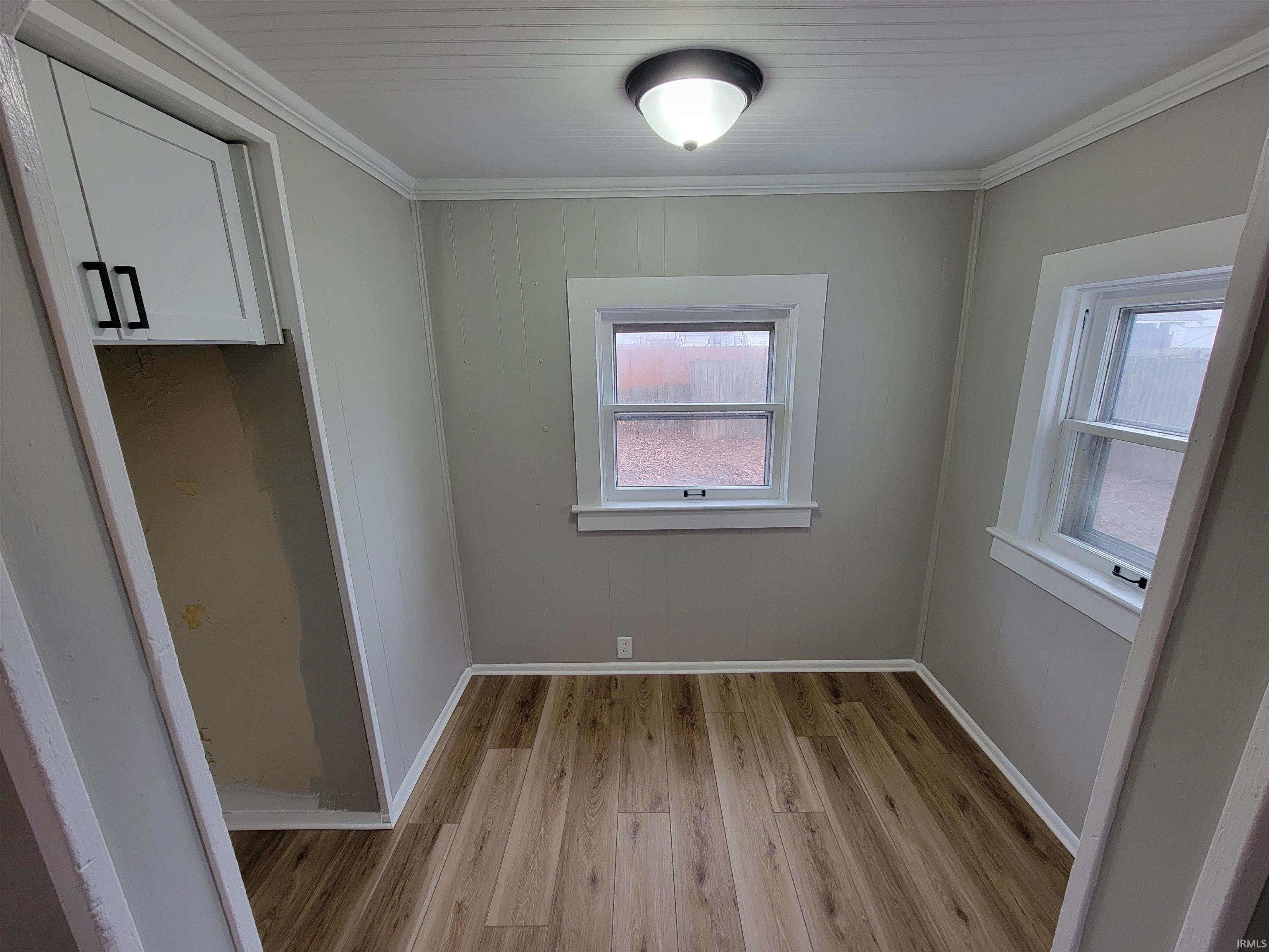 Unfurnished dining area with light wood-type flooring and ornamental molding