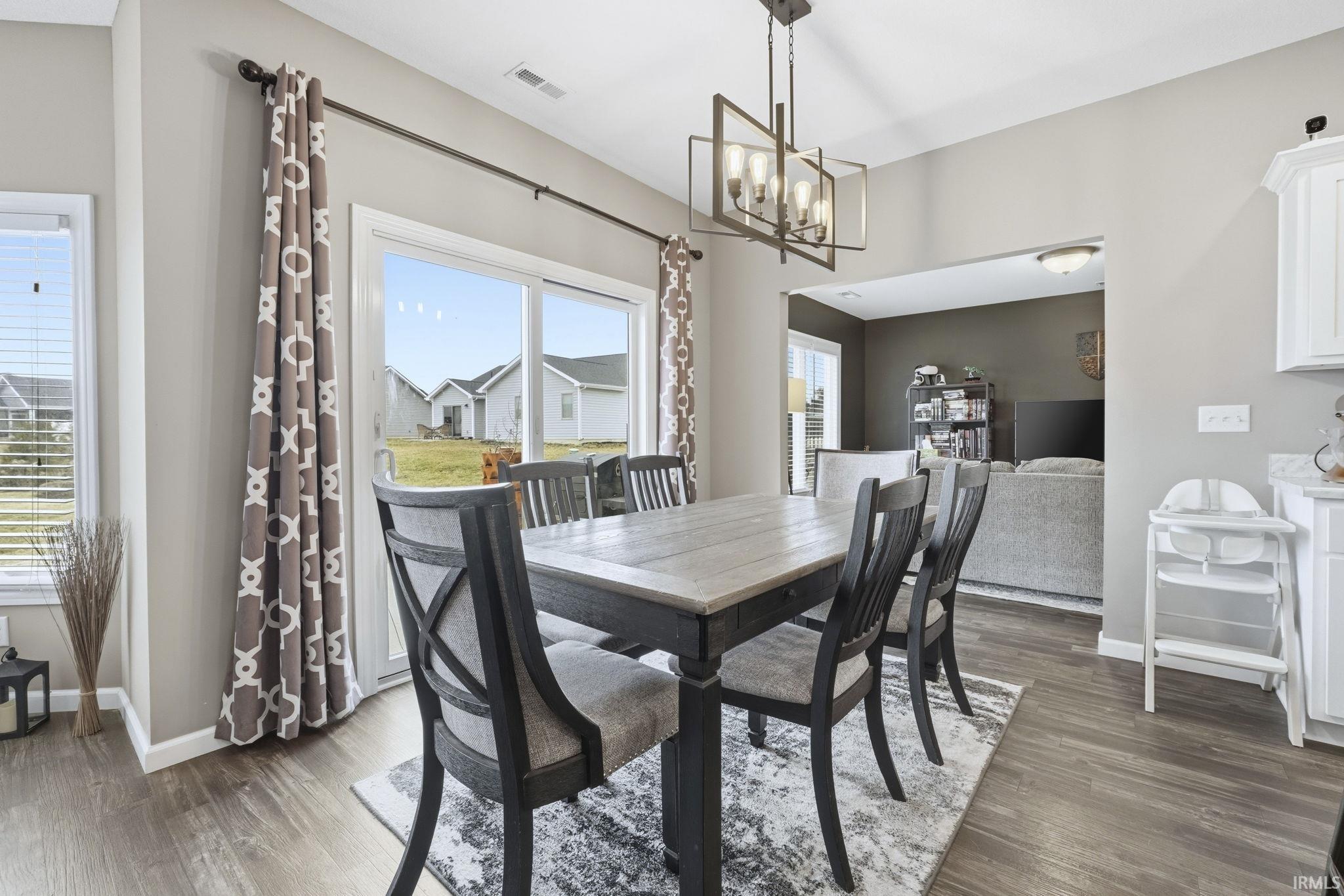 Dining area with dark wood finished floors and suspended lighting