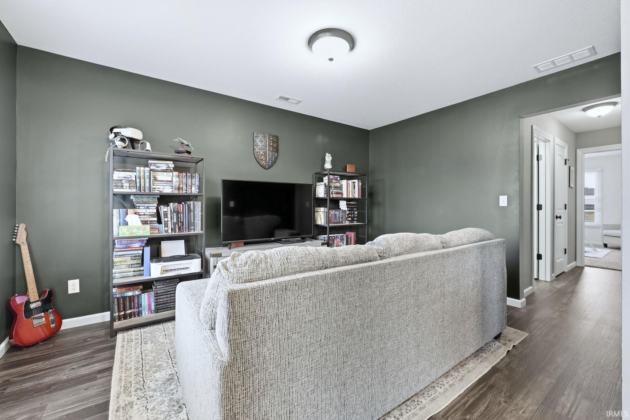 Living area featuring baseboards and dark wood-type flooring