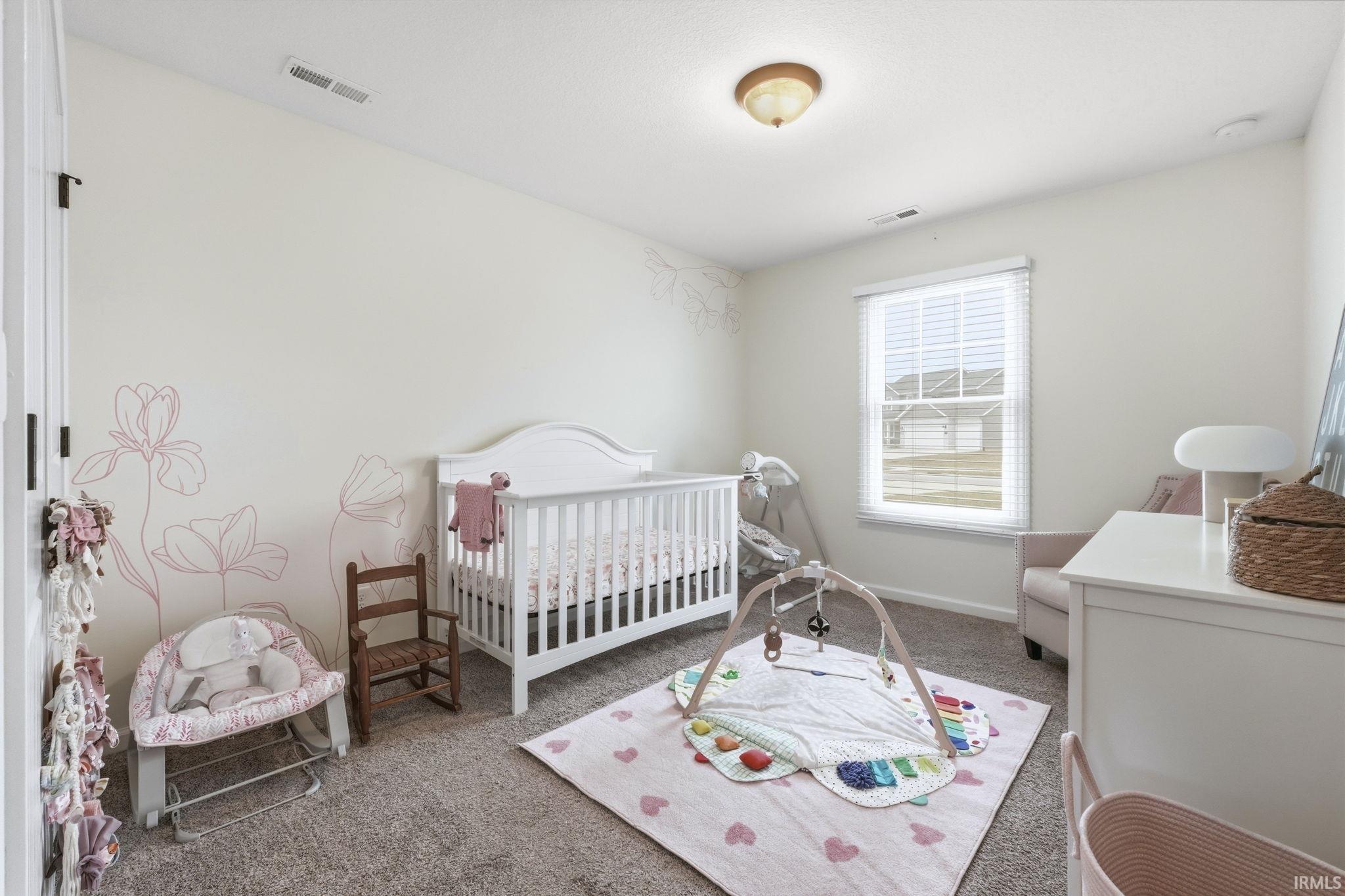 Carpeted bedroom featuring a crib and baseboards