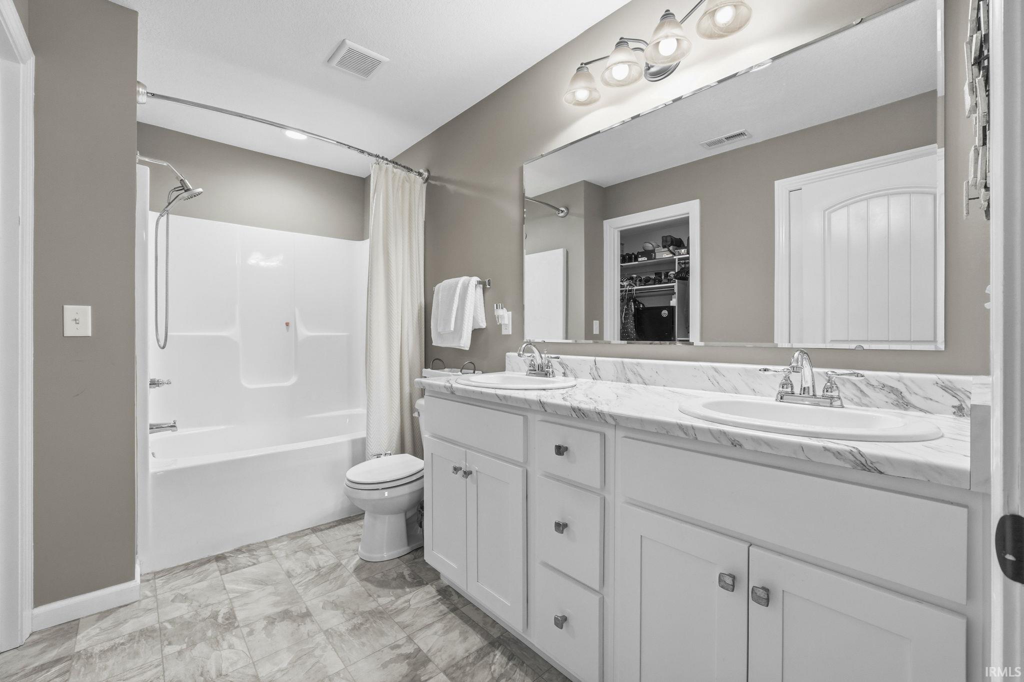 Bathroom with double vanity and shower / tub combo with curtain