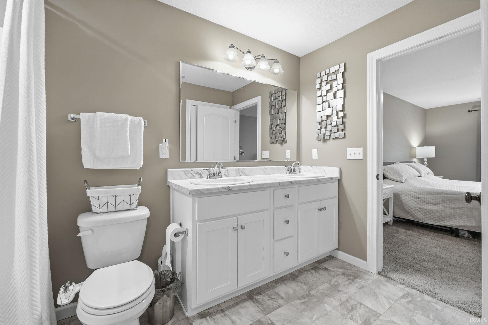 Ensuite bathroom with double vanity and light colored carpet