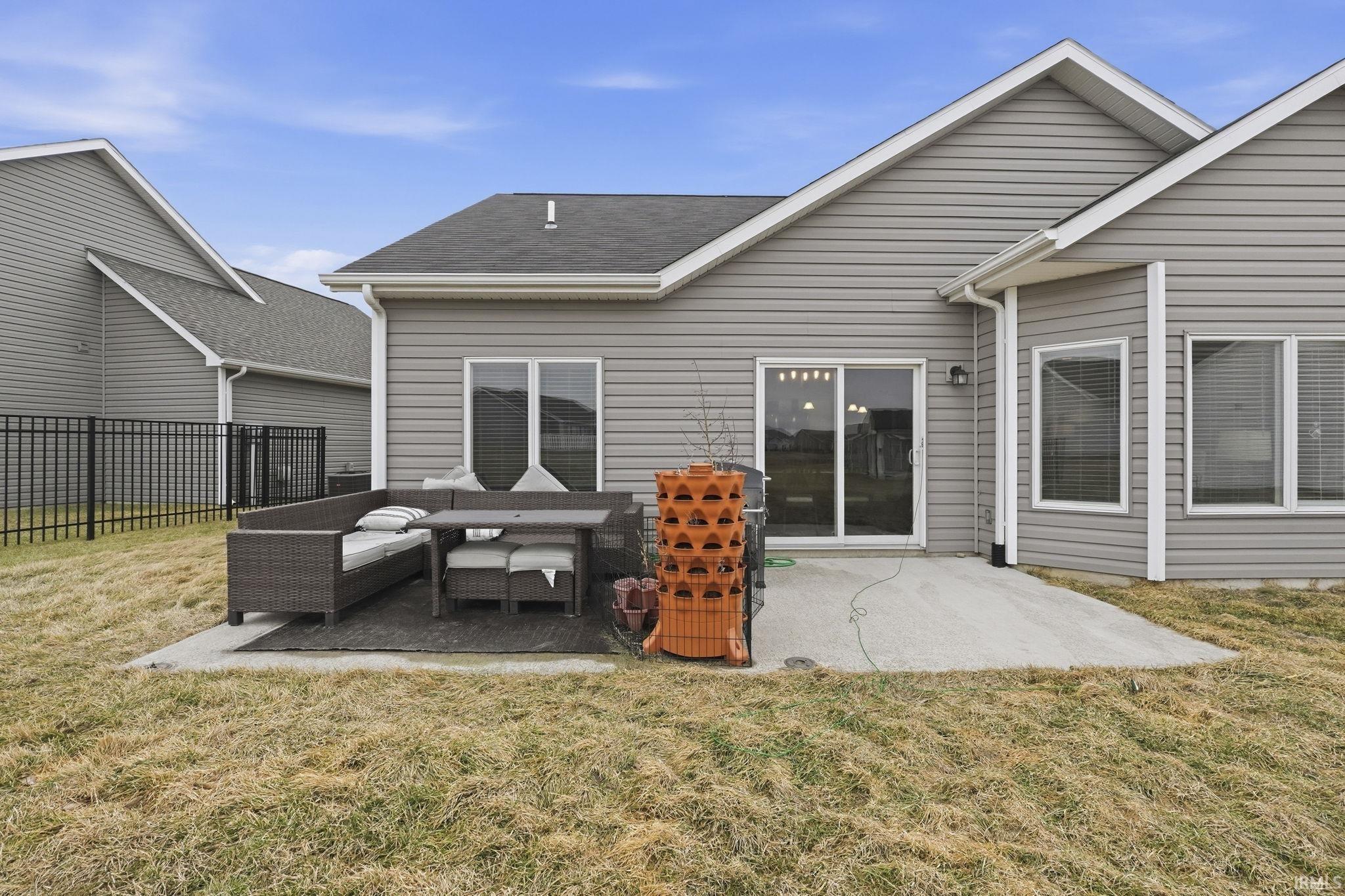 Rear view of house with a patio area, roof with shingles, and outdoor furniture