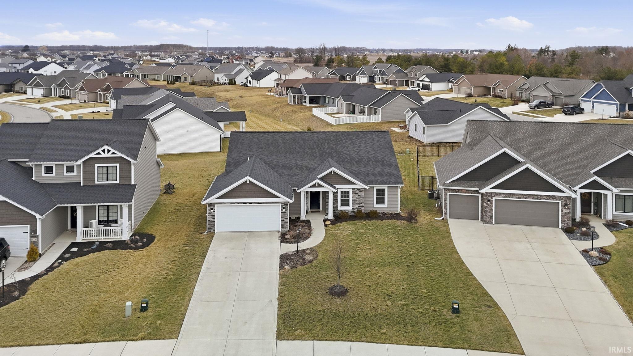 View of front of property featuring stone siding, driveway, roof with shingles, and a residential view