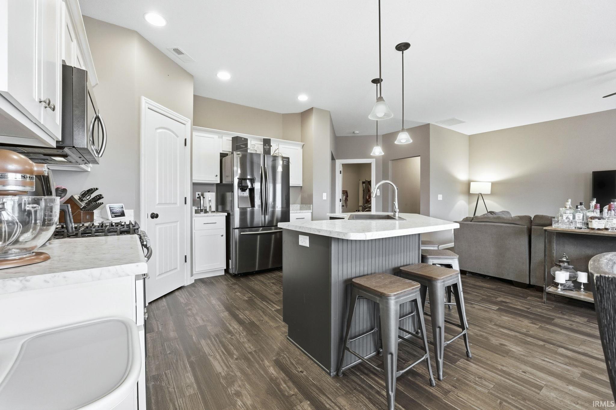 Kitchen with a kitchen island with sink, stainless steel appliances, a breakfast bar, pendant lighting, and open floor plan