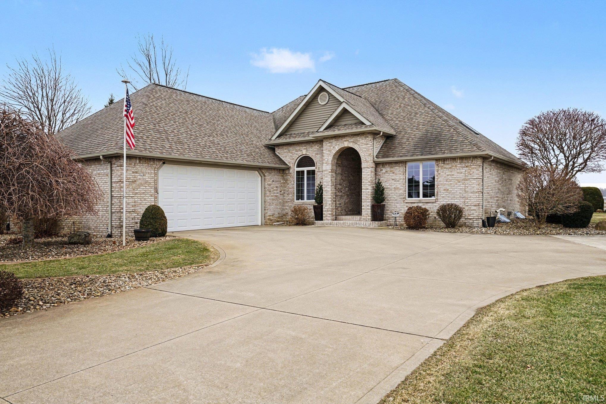 View of front of property with a garage, roof with shingles, brick siding, and driveway