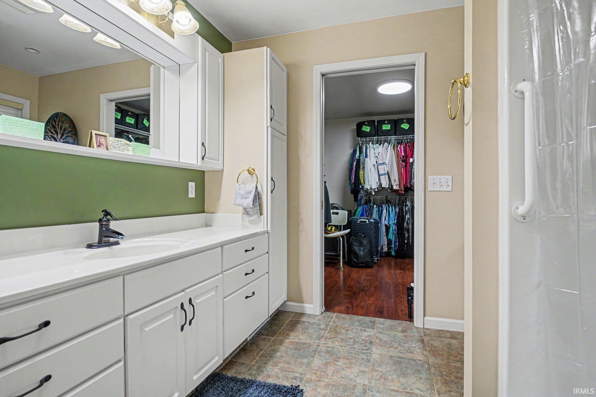 Bathroom featuring vanity, a walk in closet, stone finish floors, and a shower with shower curtain