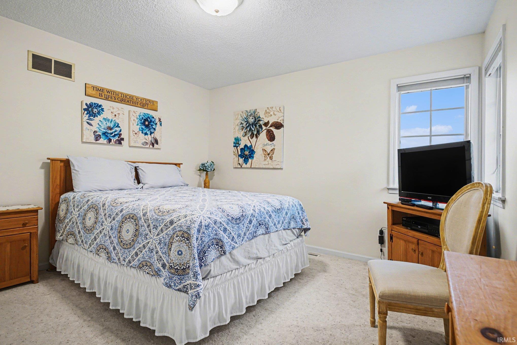 Bedroom featuring a textured ceiling and light colored carpet