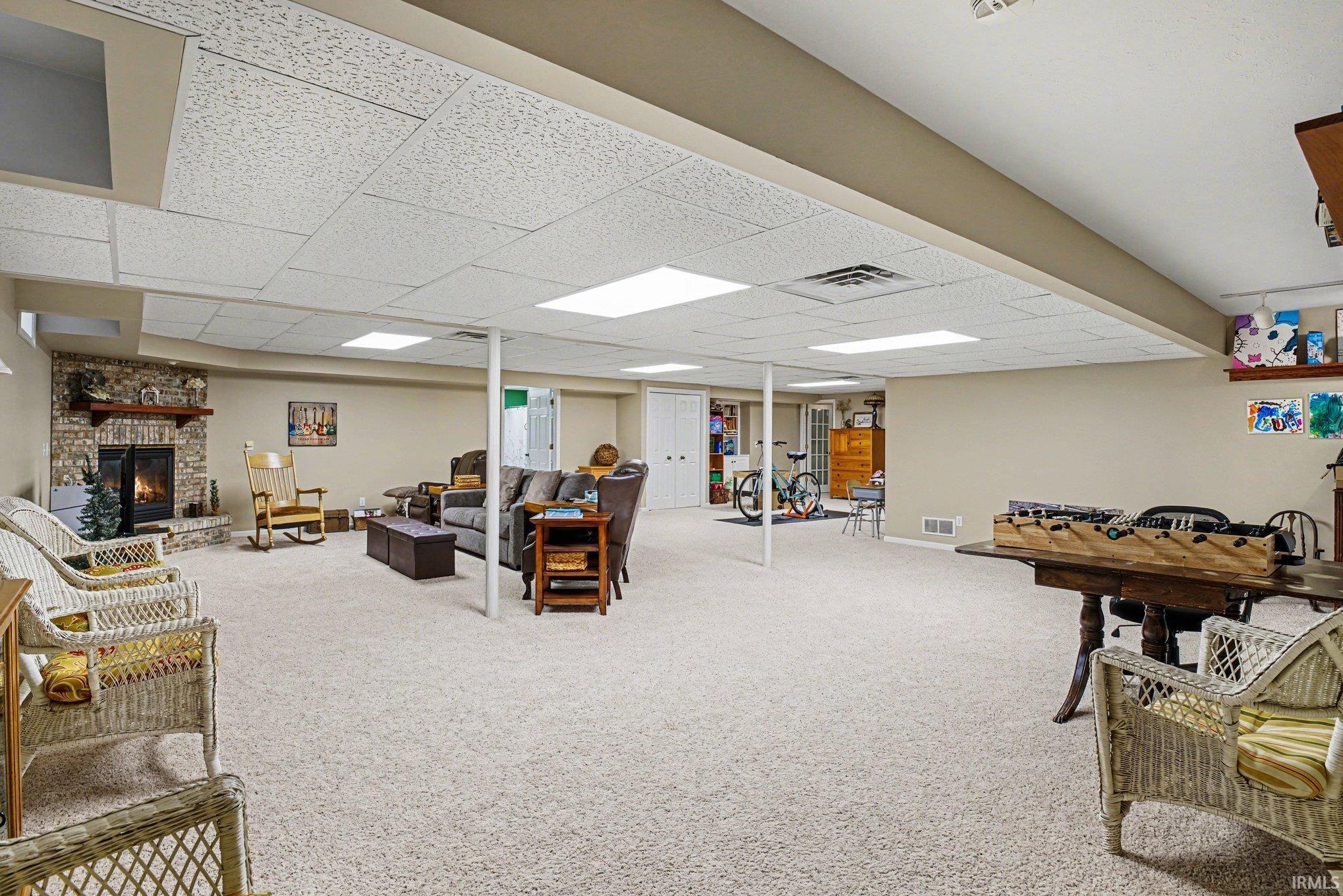 Rec room featuring carpet, a drop ceiling, and a large fireplace