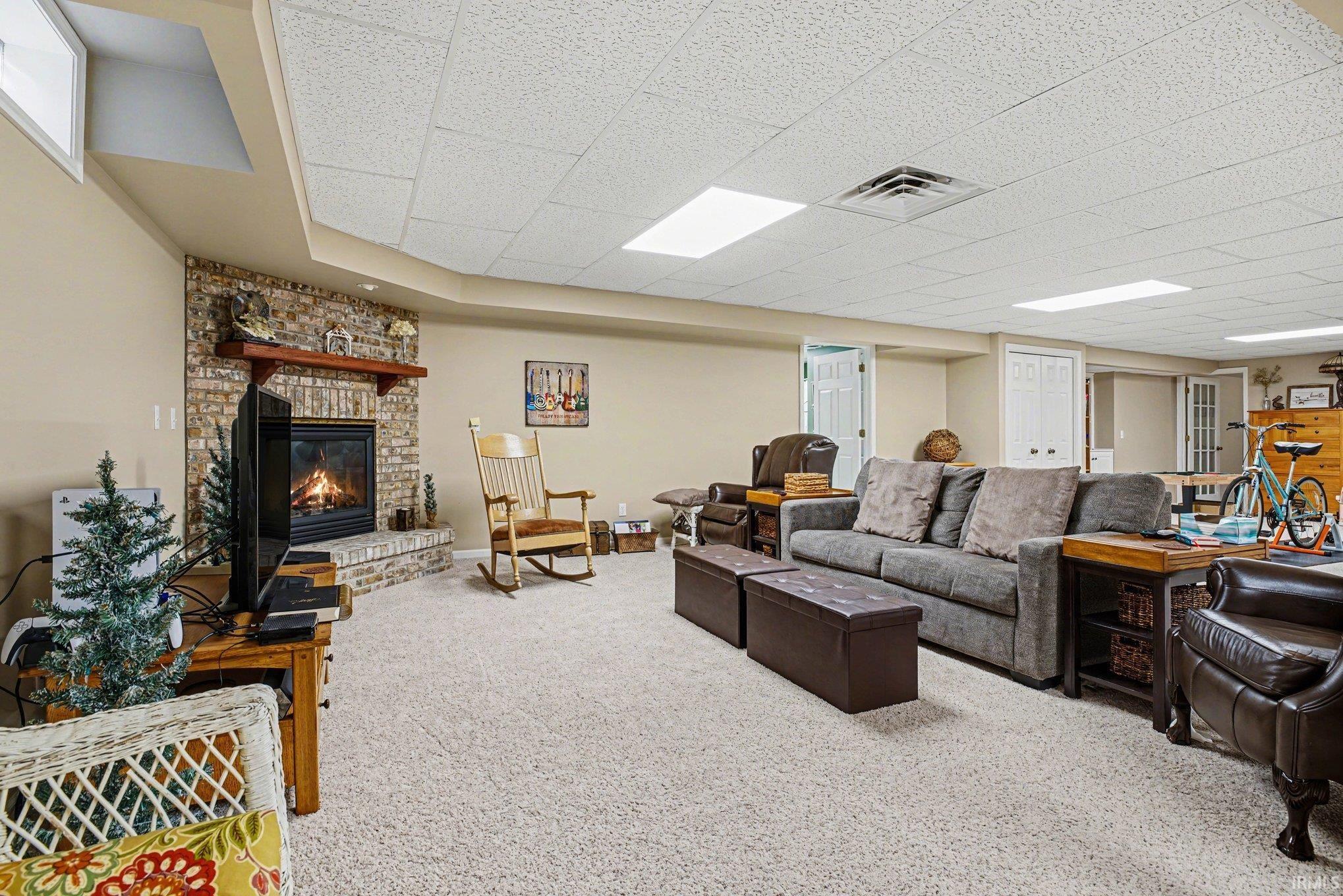 Carpeted living area featuring a fireplace and a drop ceiling