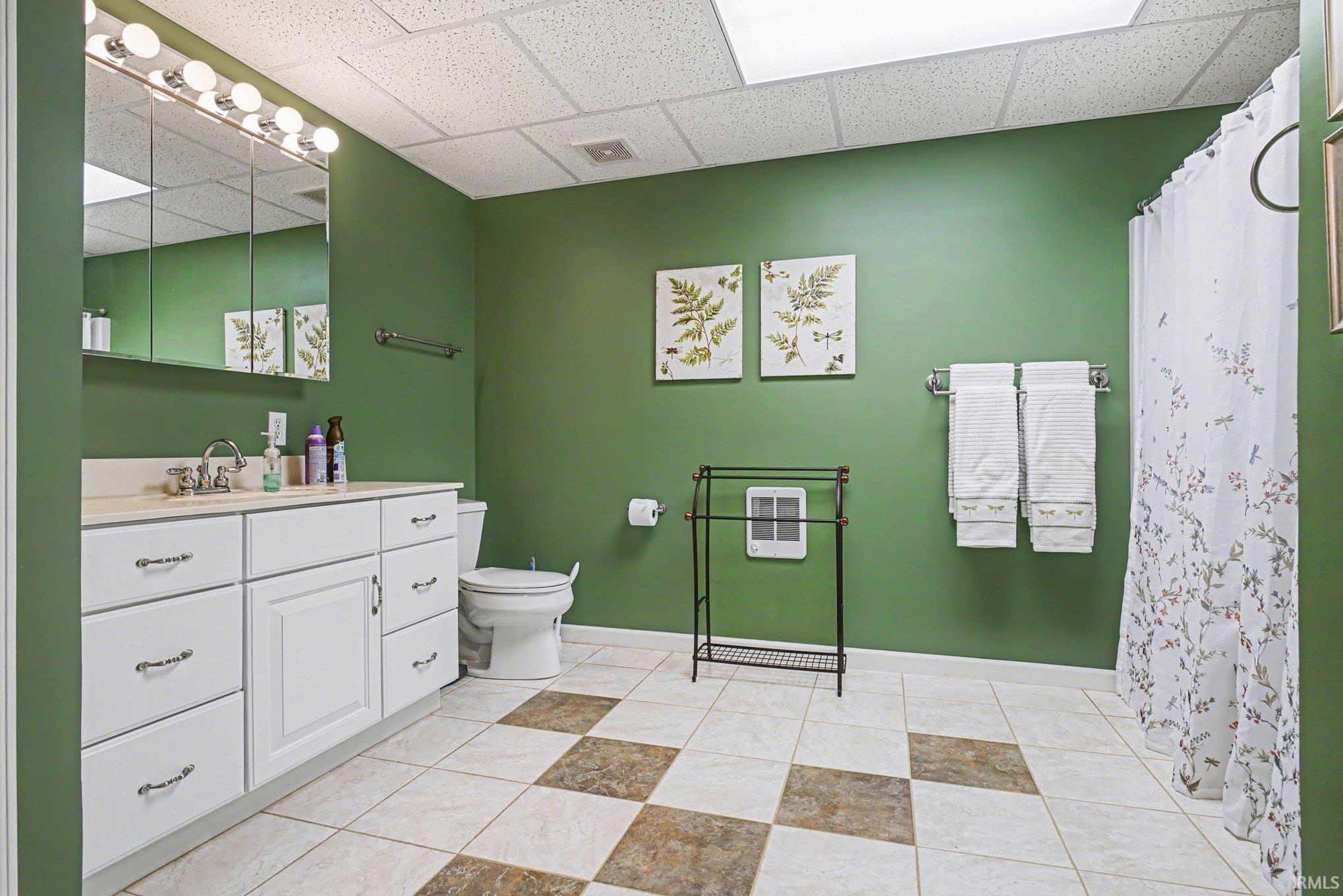 Full bathroom featuring a drop ceiling, vanity, a shower with curtain, and light tile patterned floors