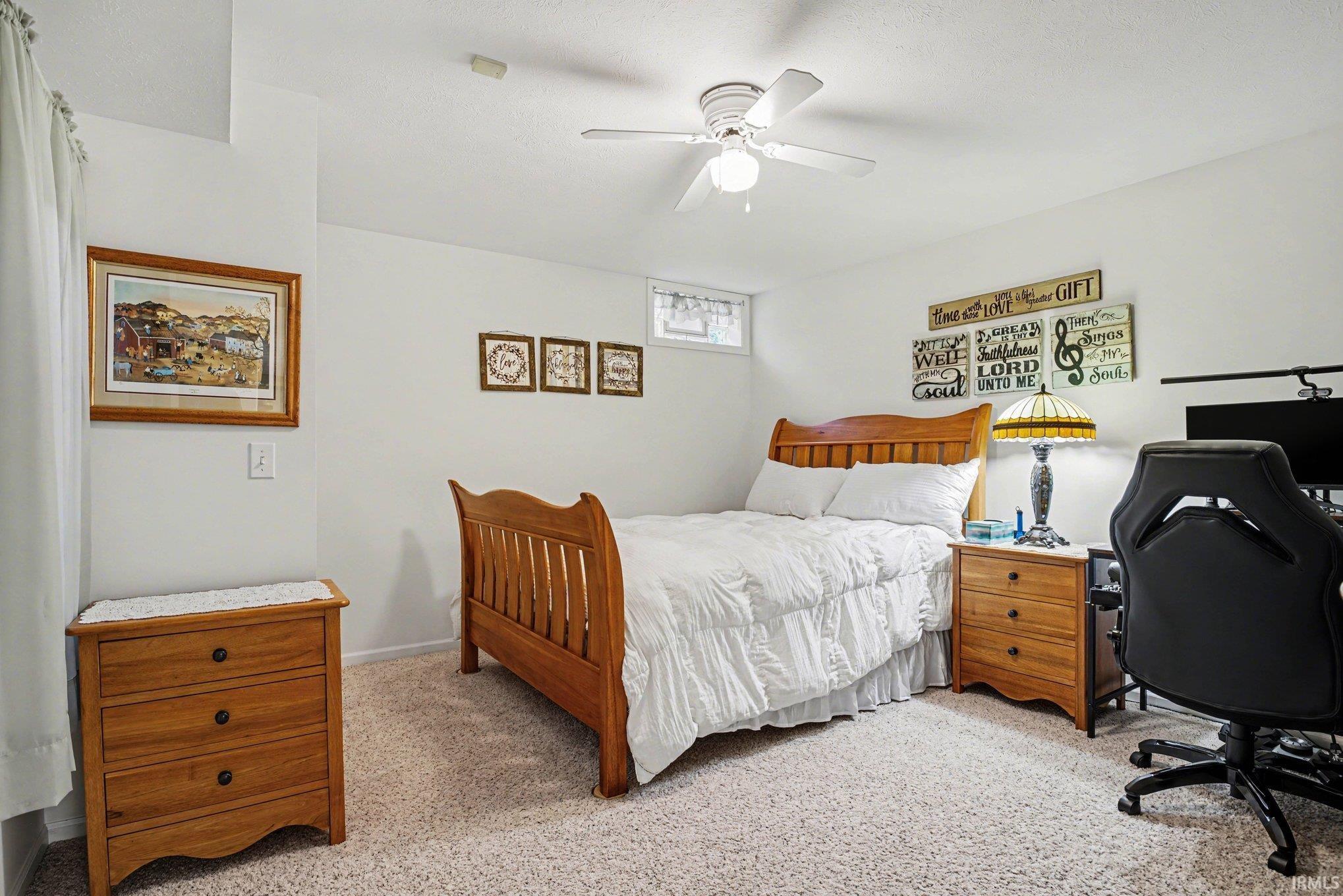 Bedroom with light carpet, ceiling fan, and a desk