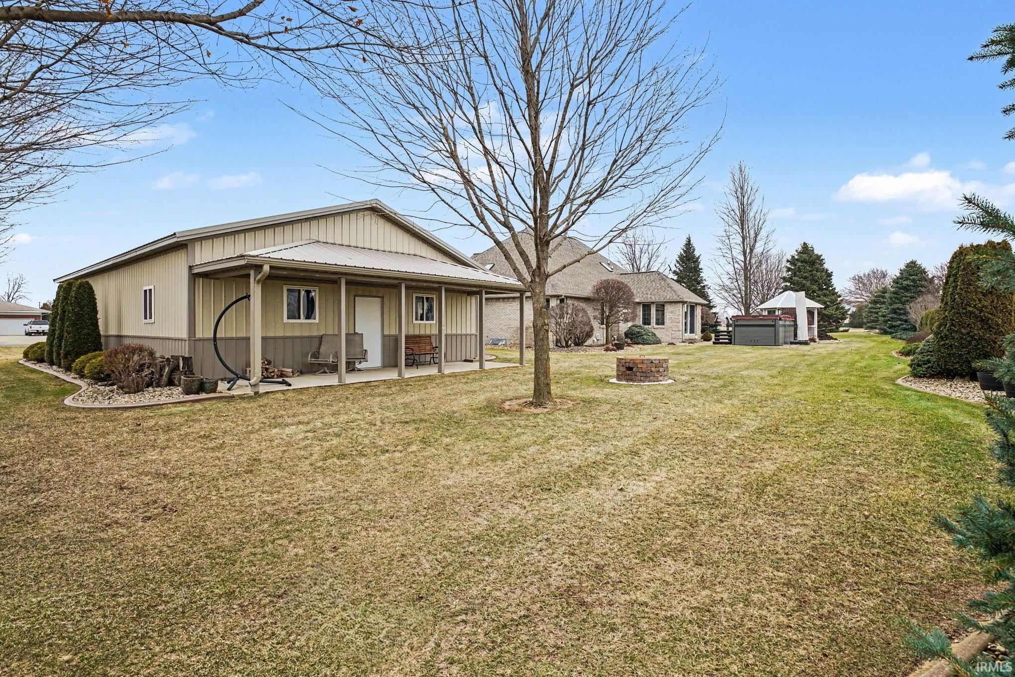 Back of property with a yard, an outdoor fire pit, and a porch