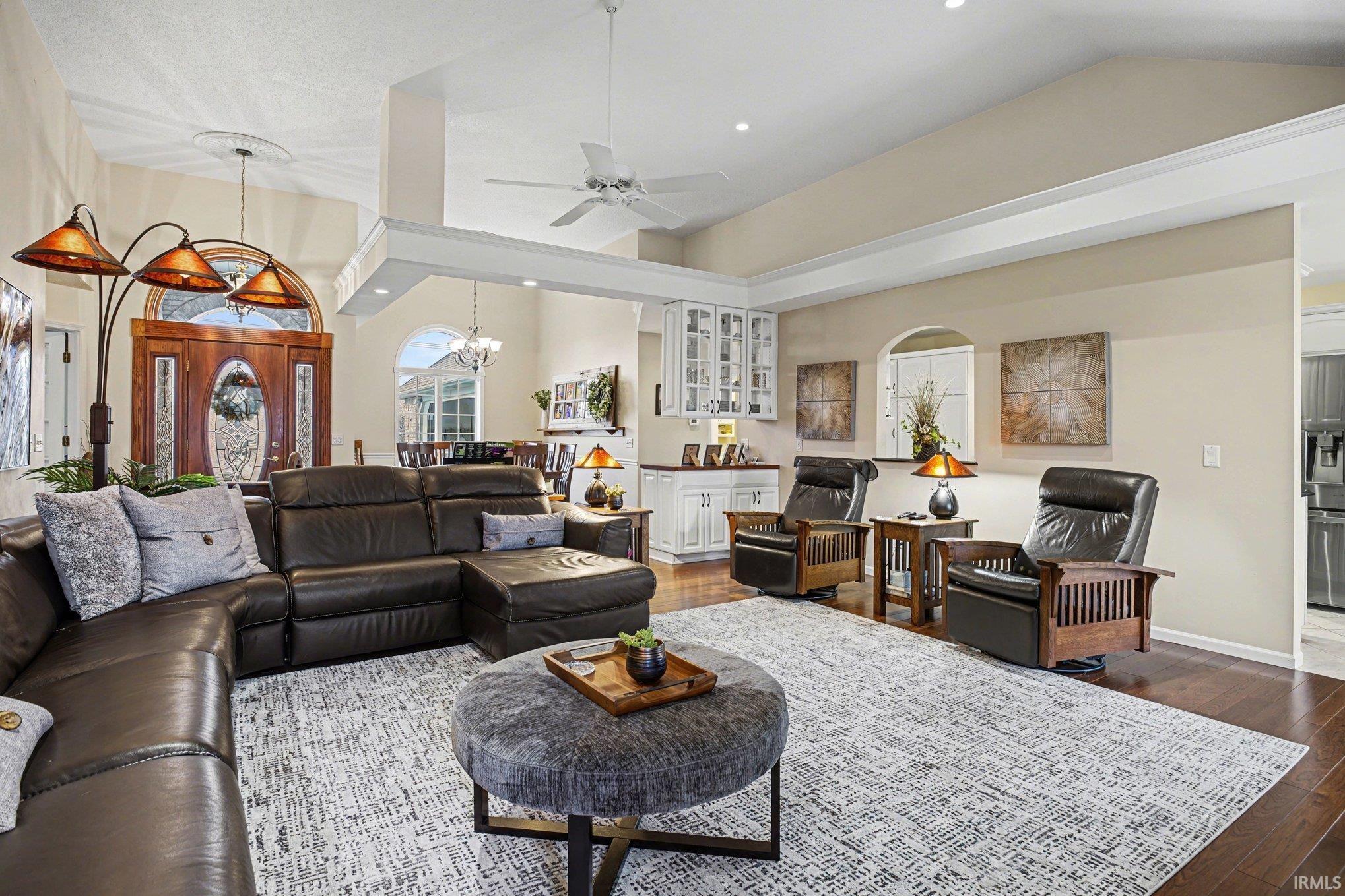 Living area featuring hanging lights, ceiling fan, dark wood-type flooring, and vaulted ceiling