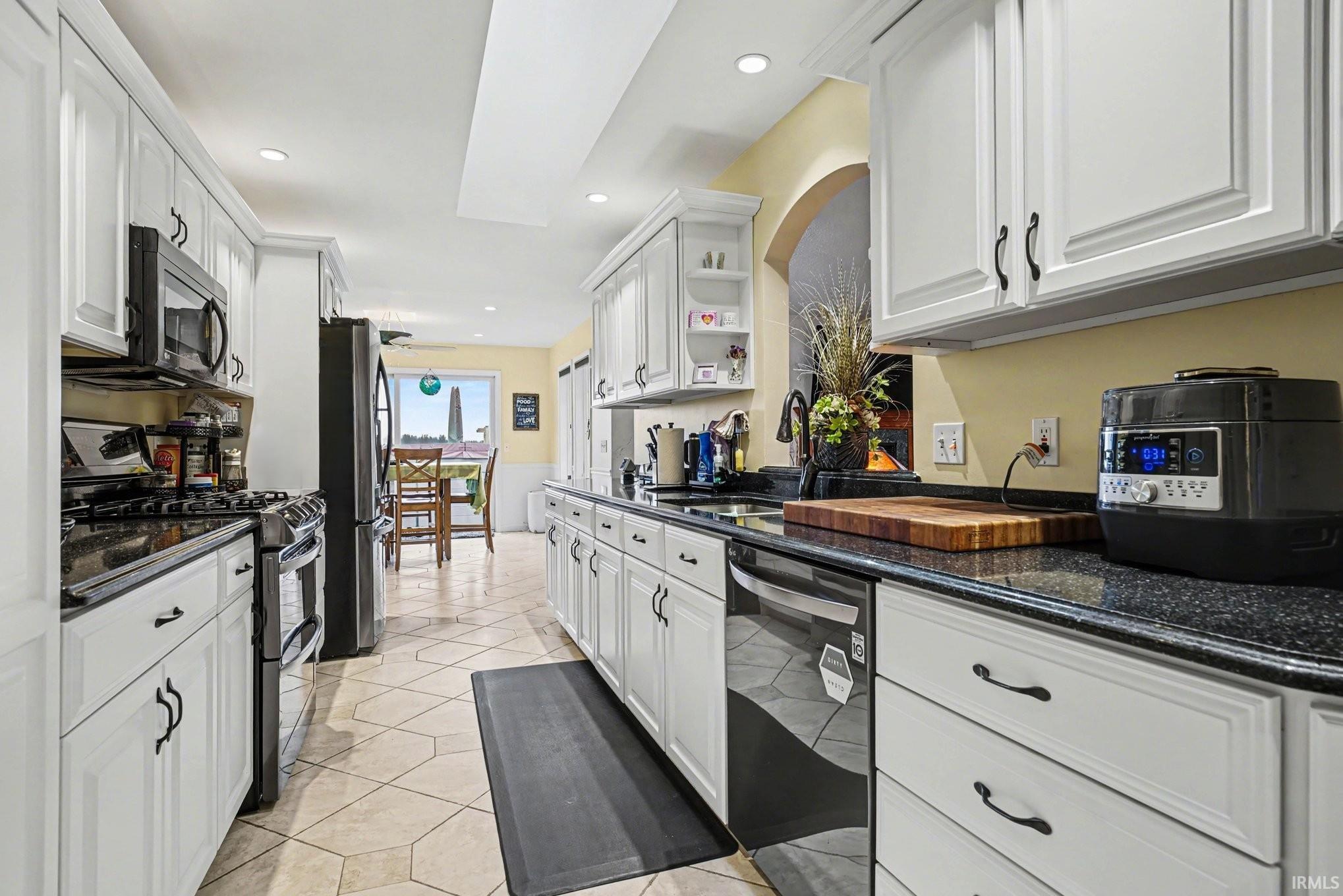 Kitchen featuring stainless steel appliances, white cabinets, dark stone countertops, recessed lighting, and open shelves