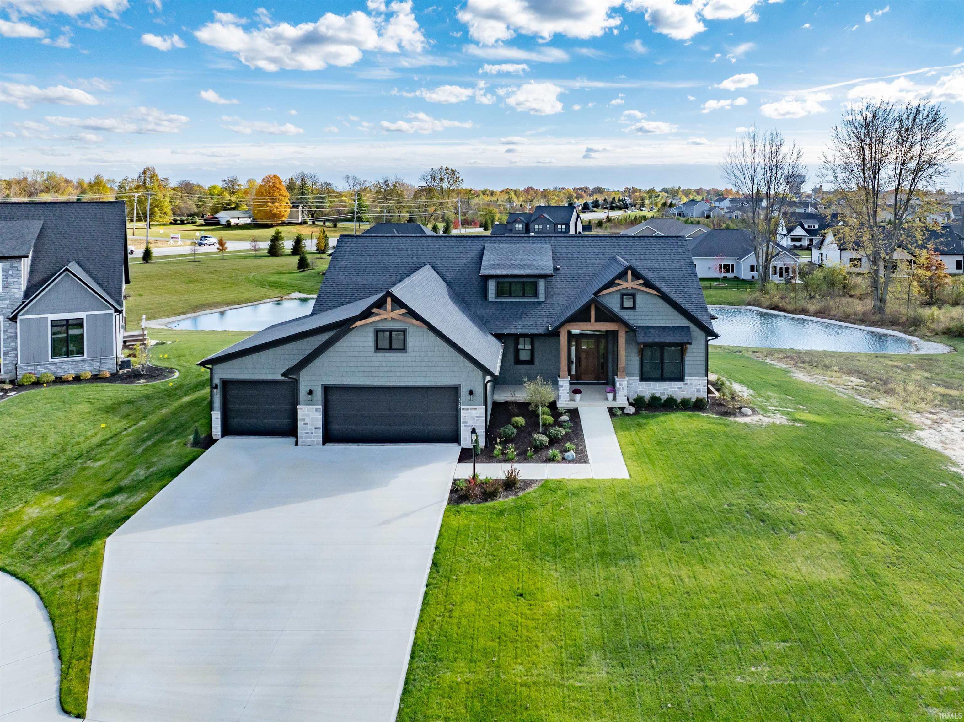 View of front of home featuring stone siding, a garage, a water view, driveway, and a front lawn