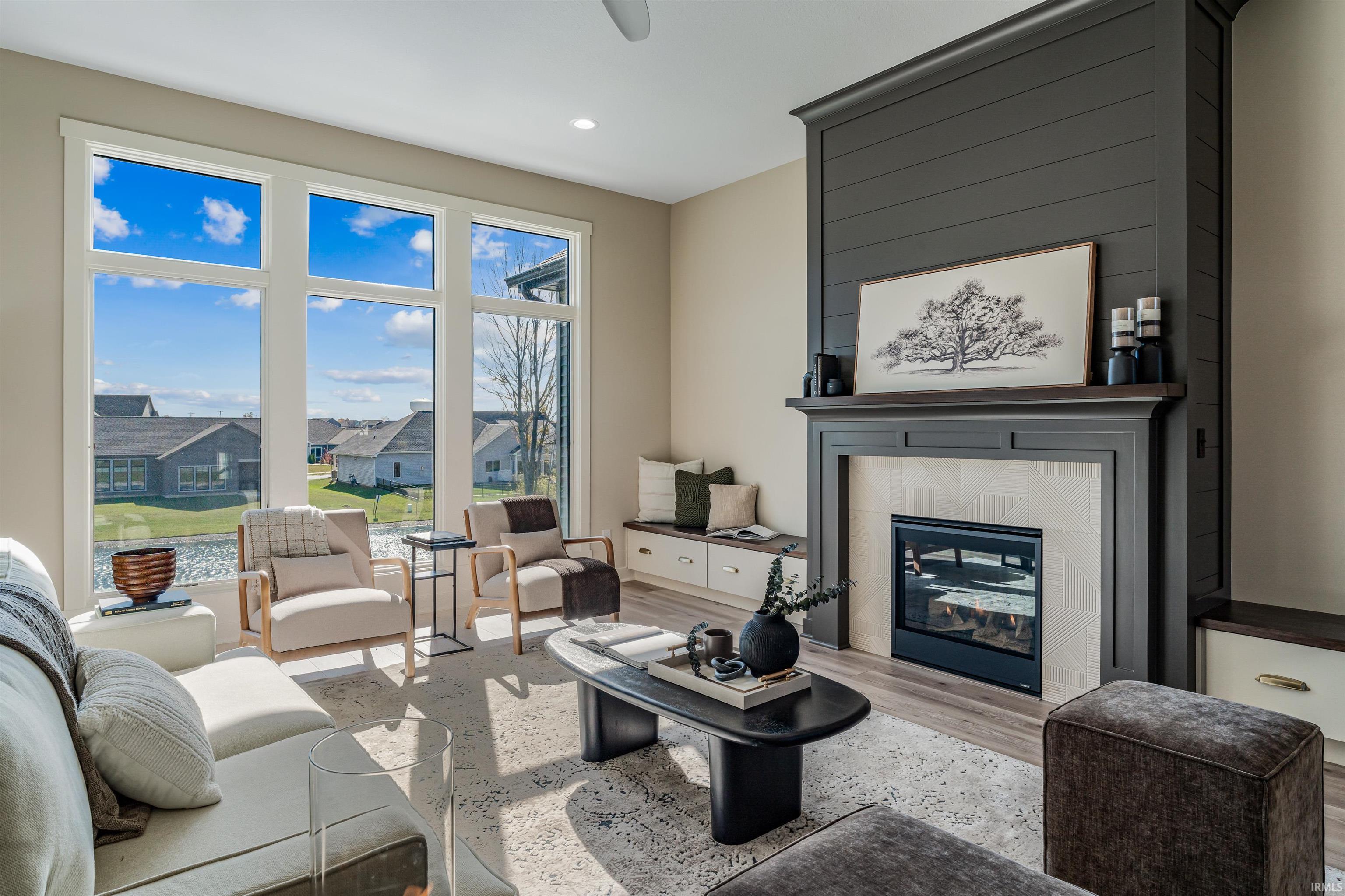 Living room with light wood-type flooring, a tiled fireplace, recessed lighting, and a residential view
