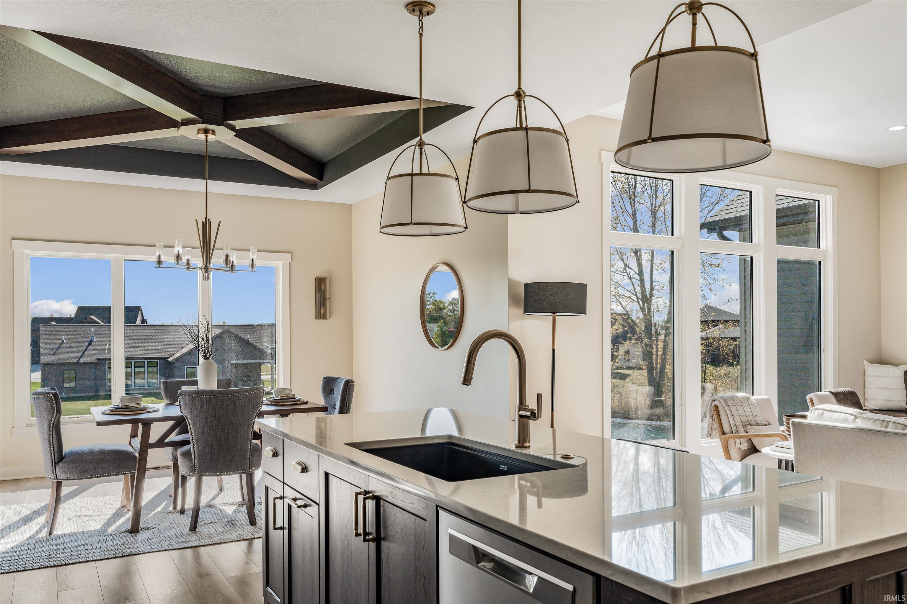Kitchen featuring a center island with sink, light stone countertops, dishwasher, light wood-style flooring, and suspended lighting