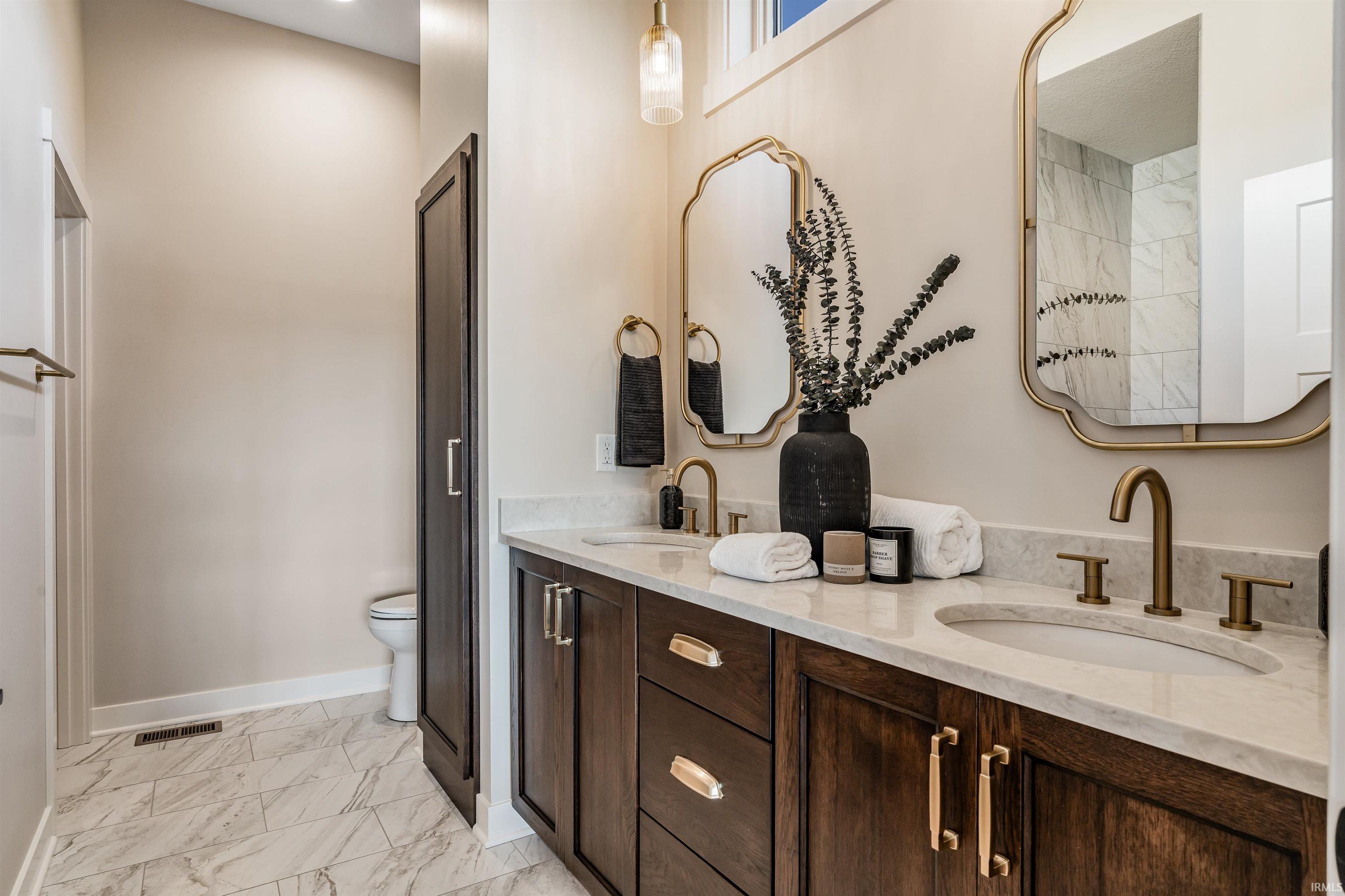 Full bathroom featuring double vanity and light marble finish floors