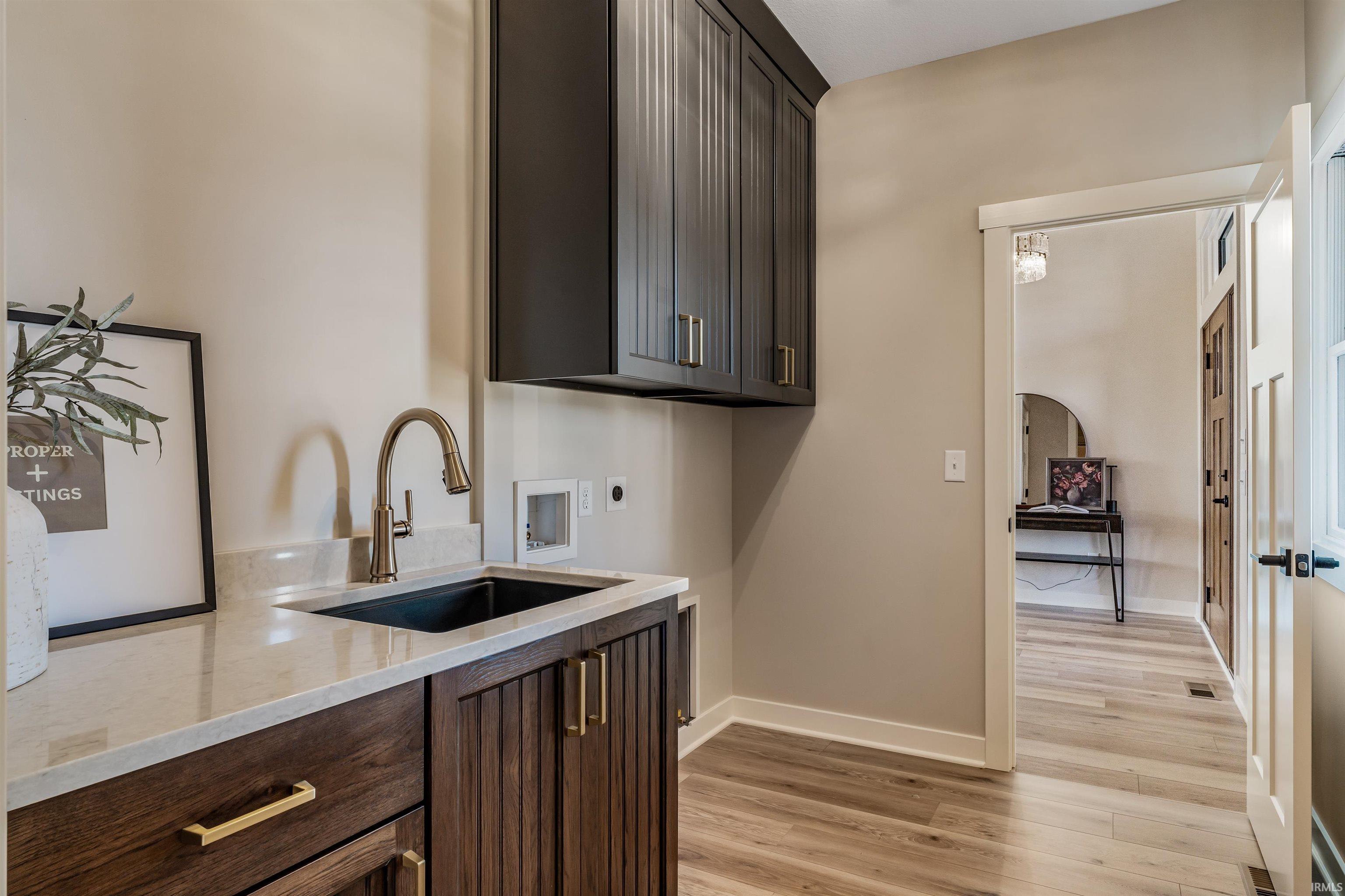 Laundry area featuring light wood-style flooring, cabinet space, and washer hookup