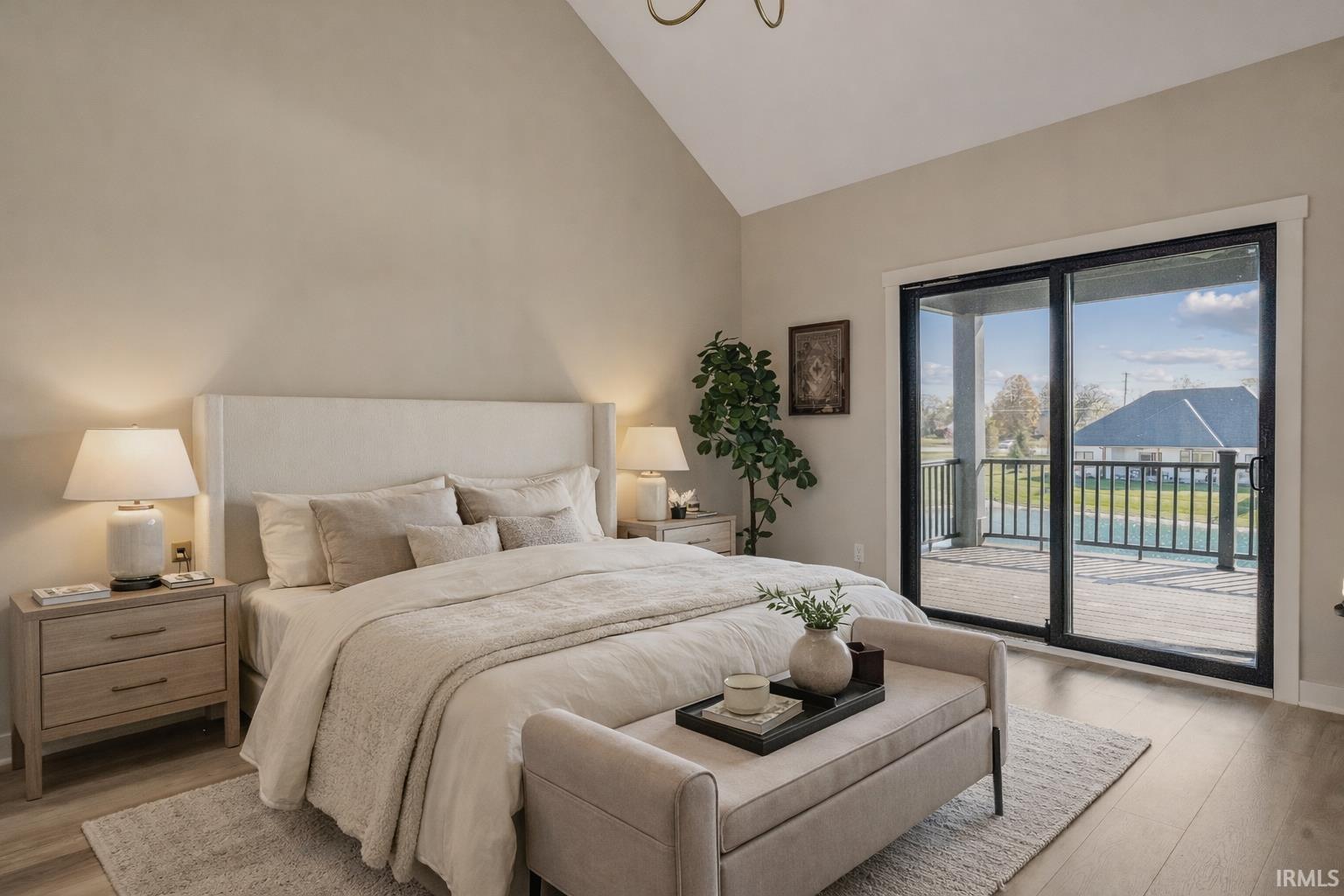 Bedroom featuring light wood finished floors, vaulted ceiling, access to outside, and hanging lights